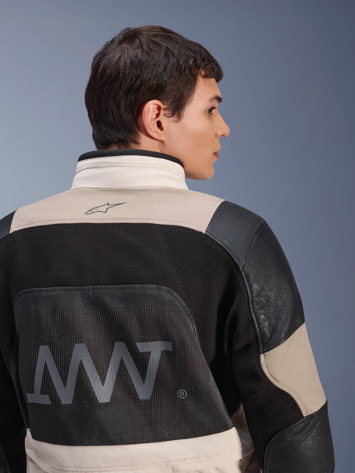 Chaqueta Alpinestars AMT-10LAB Drystar® XF, vista posterior en modelo masculino, combinación de colores White Sand Aluminum Camo y negro, con gran logotipo AMT, paneles de ventilación de malla y refuerzos de cuero, ropa técnica de motociclismo de aventura