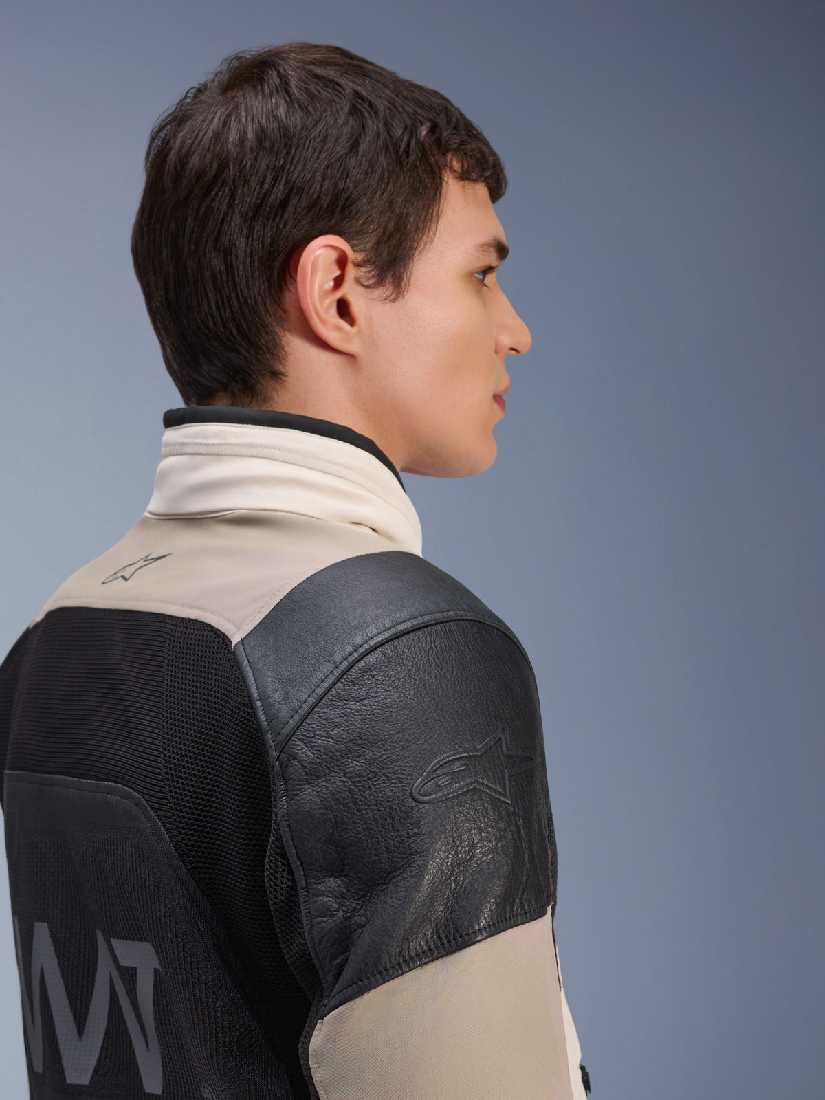 Alpinestars AMT-10LAB Drystar® XF Jacket, chaqueta de moto de aventura, color arena blanca y negro, perfil lateral que muestra el hombro de cuero negro con logo en relieve, panel trasero de malla MATYRX® con marca AMT y diseño modular protector para todo clima.