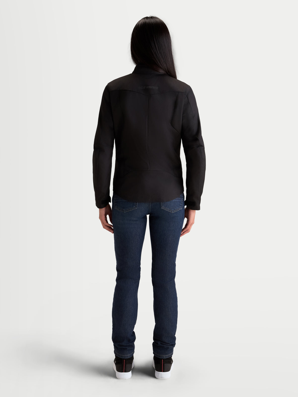 Alpinestars Stella C-1 Waterproof Chaqueta, chaqueta de moto urbana para mujer, negra, vista trasera que muestra la construcción ergonómica trasera y el tejido de poliéster impermeable, vestida por una modelo