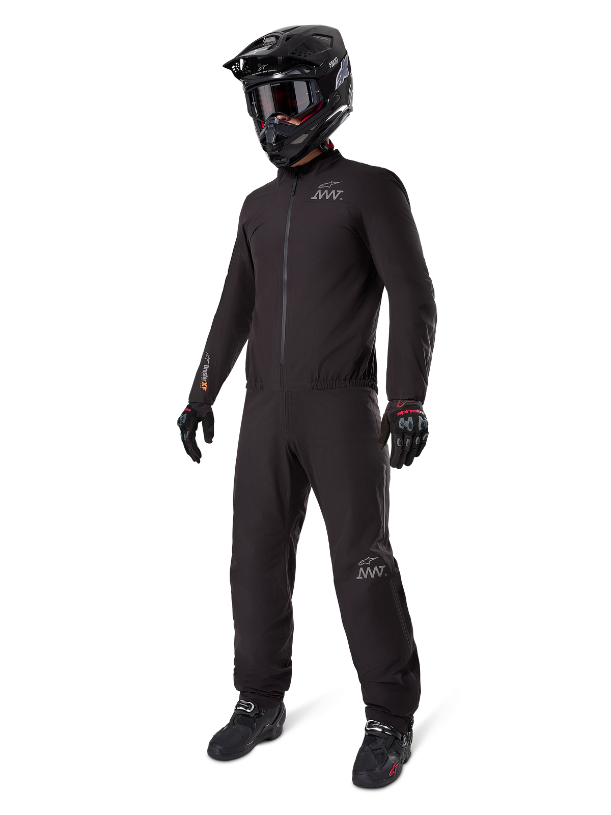 Alpinestars AMT-8 Stretch Drystar XF Liner, traje de touring de aventura completamente negro, chaqueta y pantalones impermeables y cortavientos, combinado con un casco de aventura negro, gafas, guantes y botas de conducción, con logotipos AMT y marca Drystar XF en las mangas y las piernas.