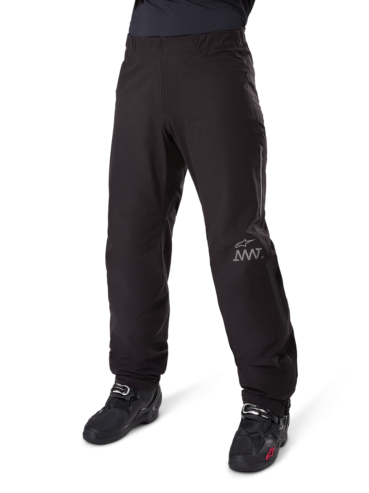 Alpinestars Amt 8 Stretch Drystar® XF Pant Liner, pantalones impermeables de moto, negros, con un logo AMT gris en la parte inferior de la pierna izquierda, usados con botas de moto negras, diseño funcional para conducción de aventura en todo tipo de clima