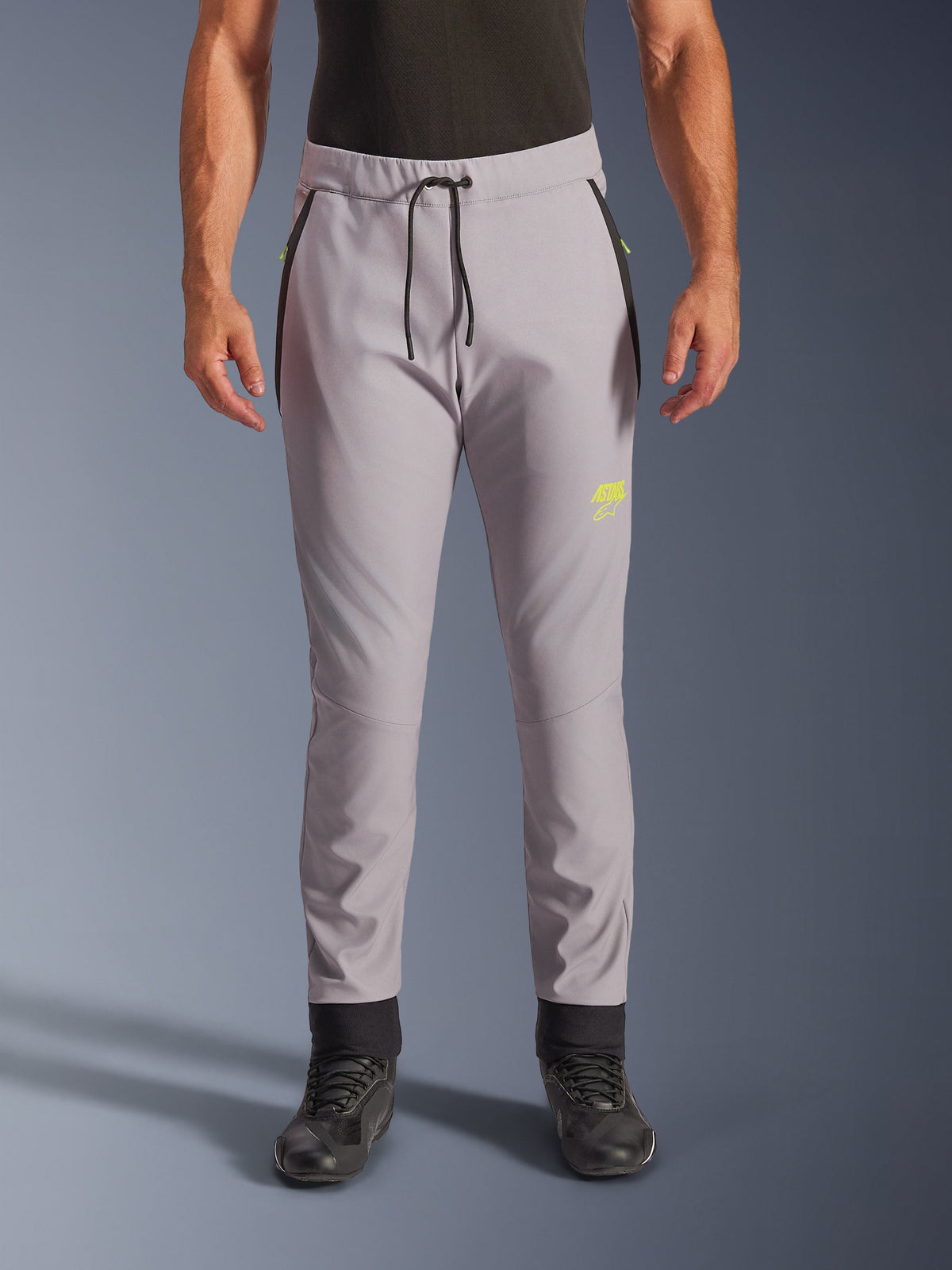 Pantalones Alpinestars Aeroshell, gris medio y amarillo flúor, pantalones de moto softshell crossover, con cintura con cordón negro, puños ajustados, logotipo amarillo en el muslo izquierdo, rodillas precurvadas y silueta deportiva estilo jogger