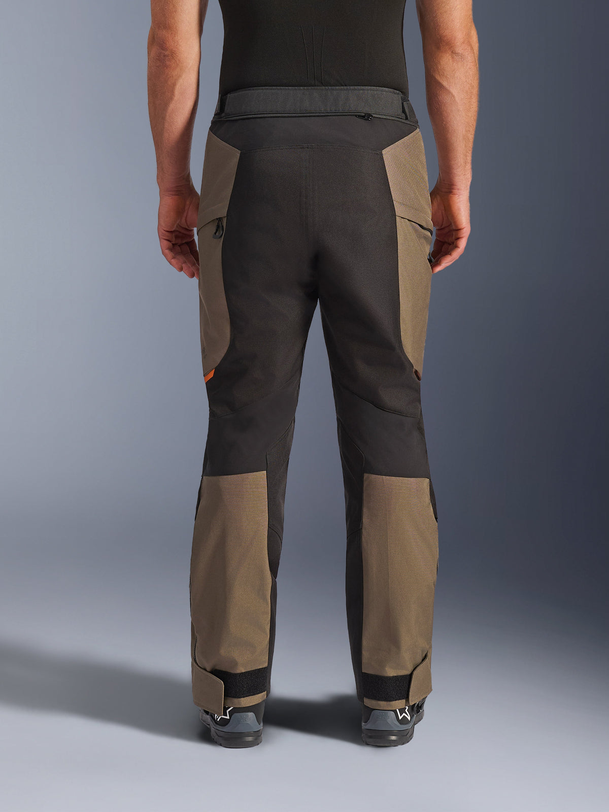 Pantalones Alpinestars Cusco Drystar®, pantalones de motociclismo de aventura, Walnut Black, vista trasera en modelo, construcción textil duradera con paneles de bloques de color, dobladillo ajustable y detalle de cintura con cremallera para touring y conducción de aventura