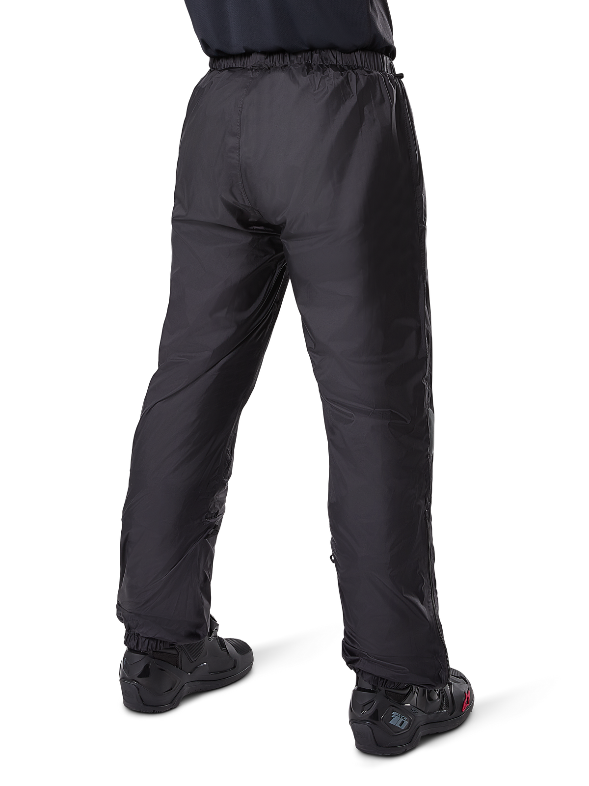 Pantalones Alpinestars Bogotá Pro Drystar® 3 Seasons, pantalones de moto adventure touring negros, vista trasera del forro impermeable Drystar® usado como sobrepantalón, combinados con botas de moto negras, construcción técnica ligera para protección climática en múltiples estaciones