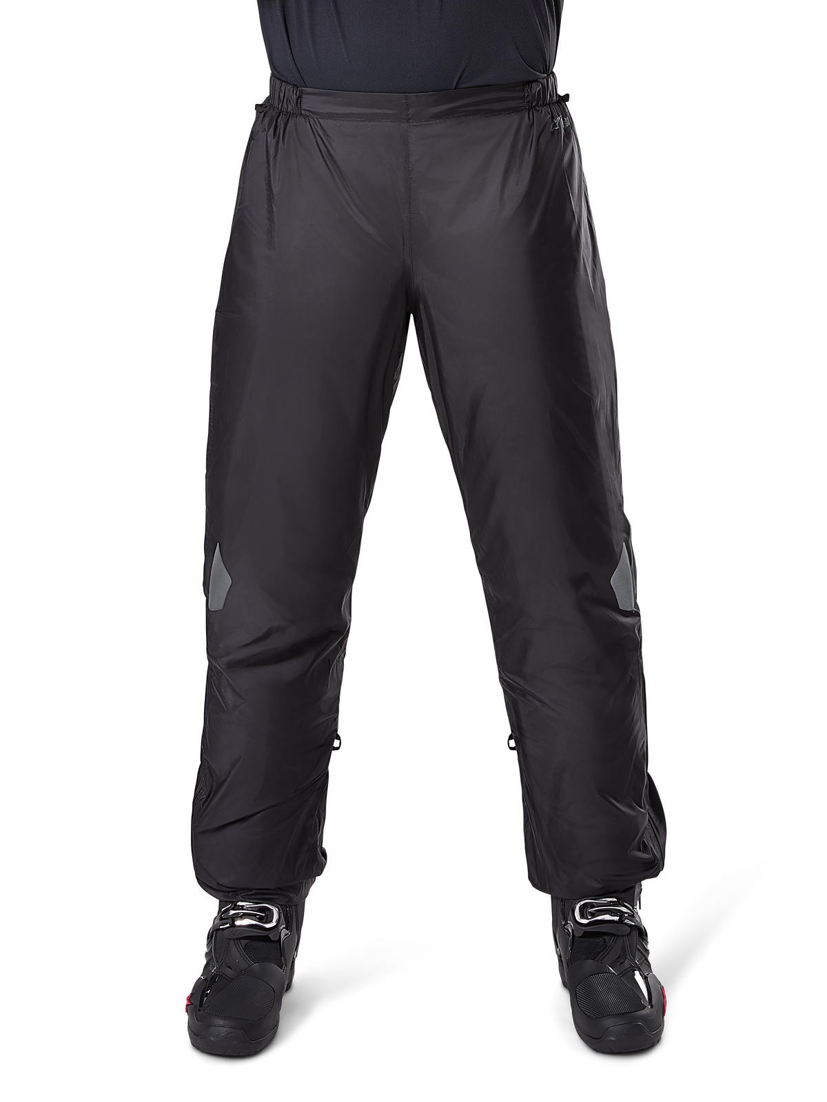 Alpinestars Bogota Pro Drystar 3 Seasons Pants, pantalones impermeables de moto, negros, tejido técnico ligero con parches reflectantes en las rodillas, usados como sobrepantalones con botas de montar negras, diseñados para protección climática en rutas de aventura