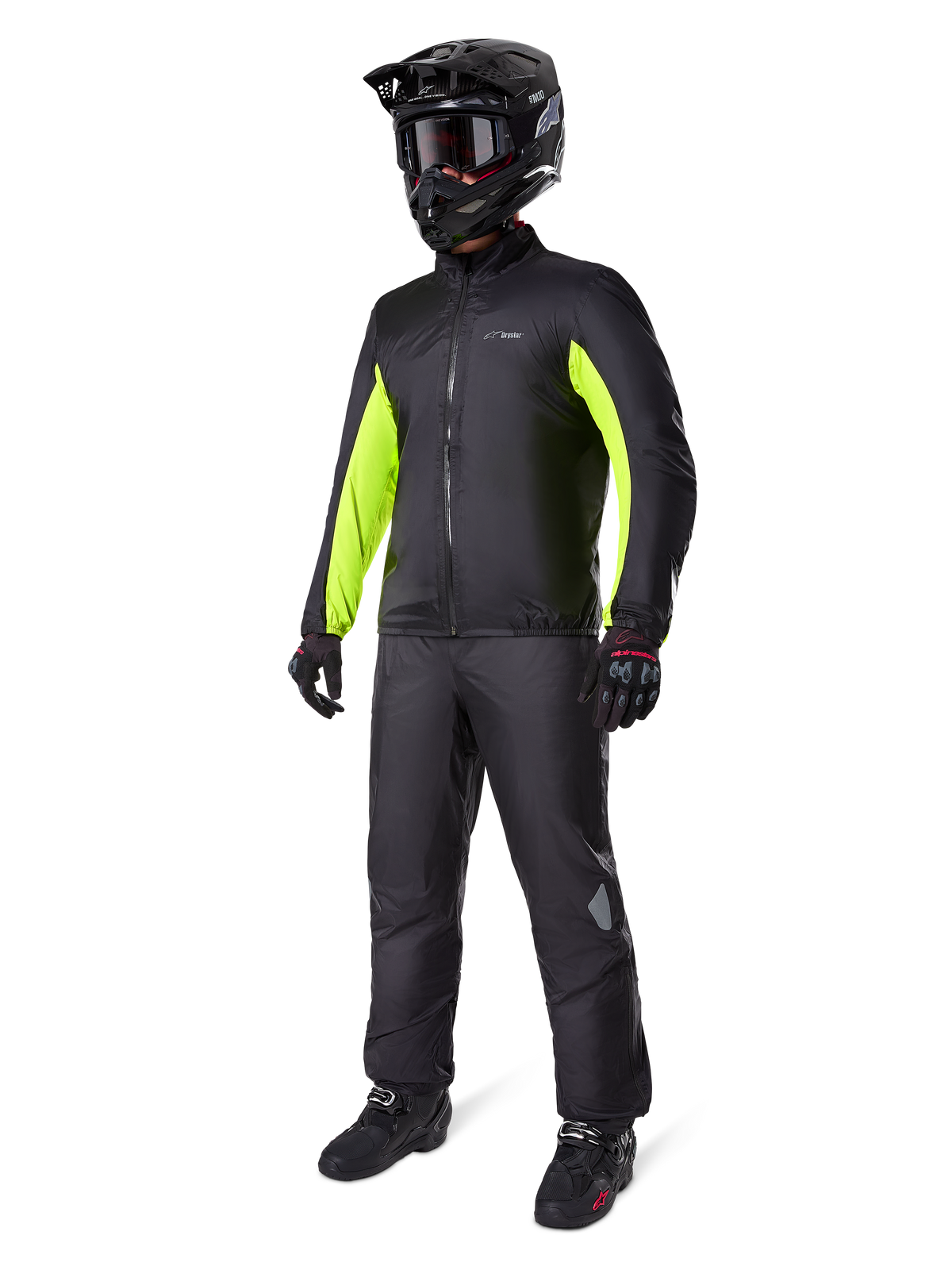 Pantalones Alpinestars Bogota' Pro Drystar® 3 Seasons, negros, piloto con equipamiento completo de adventure touring que incluye una chaqueta negra con detalles en amarillo neón, casco negro, guantes y botas, con la membrana impermeable Drystar® usada sobre los pantalones