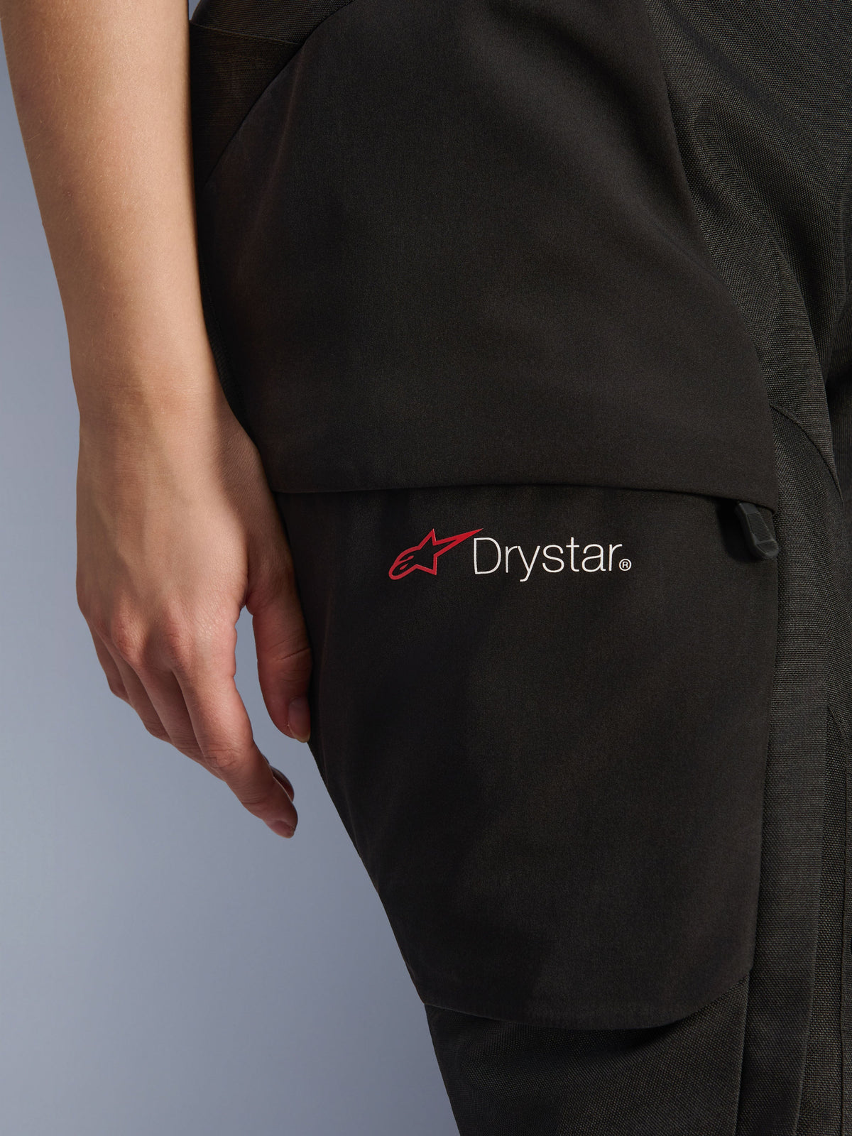 Alpinestars Woman Stella Andes V4 Drystar® Pants, Adventure Motorcycle Pants, Black, close-up of thigh area featuring the Drystar logo and red star icon, durable textile material with cargo pocket and zipper detail