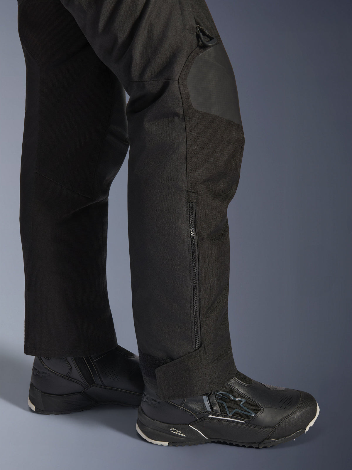Alpinestars Stella Andes V4 Drystar® Pants, Woman's Motorcycle Pants, Black, close-up of lower leg featuring side zipper and adjustable ankle cuff, worn with black Alpinestars riding boots