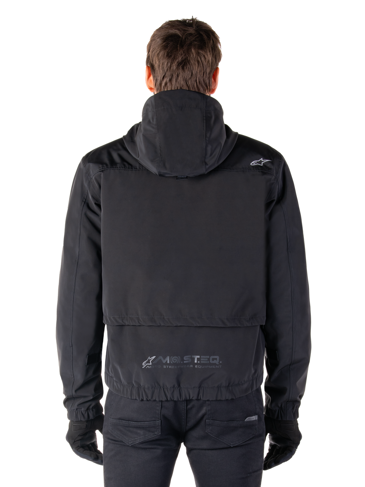 Parka impermeable Alpinestars Mootant, chaqueta de moto negra, vista trasera que muestra el diseño con capucha, con un pequeño logotipo Astar en el hombro y marca reflectante MO.ST.EQ. en la parte inferior de la espalda