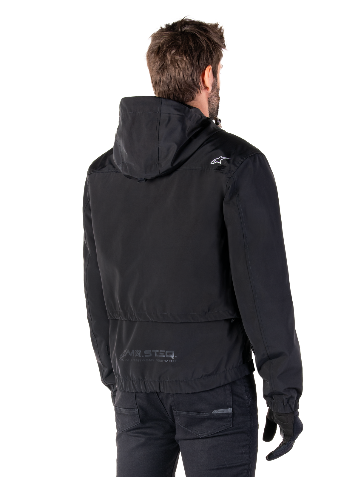 Parka impermeable Alpinestars Mootant, chaqueta de moto negra, vista trasera que muestra el diseño con capucha, logotipo blanco en el hombro y marca reflectante MO.ST.EQ. en la parte baja de la espalda, equipamiento de conducción urbano contemporáneo