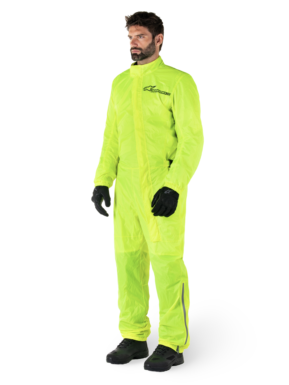 Alpinestars Hurricane Rain V2 Suit, One-piece waterproof motorcycle suit, Yellow Fluo, worn with black gloves and boots, featuring a black Alpinestars logo on the chest and reflective detailing on the legs