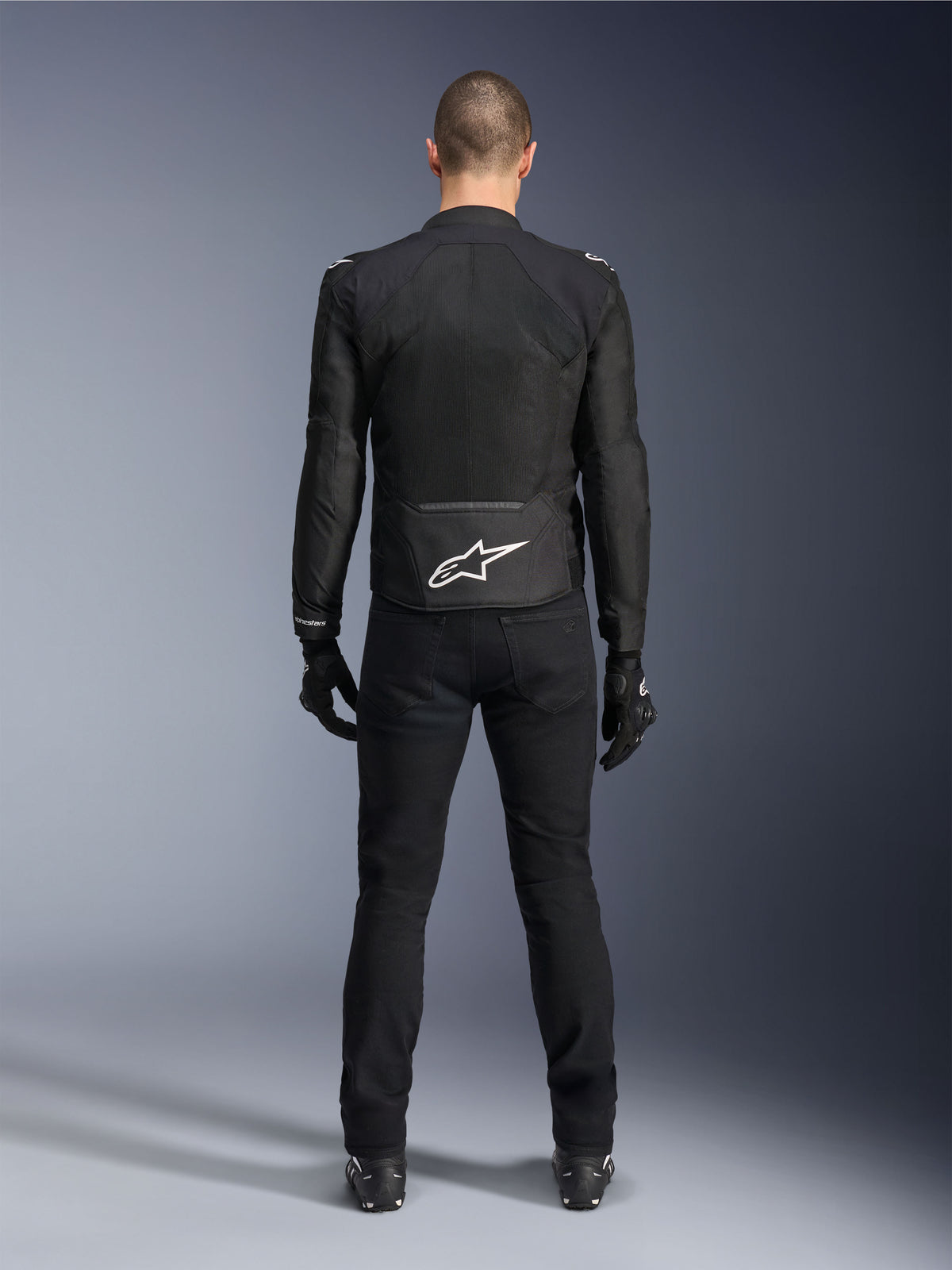 Alpinestars Viper Air V4 Jacket, Black Textile Motorcycle Jacket, back view with white Alpinestars star logo on lower back, worn with black riding pants and gloves, summer gear for road and sport riding