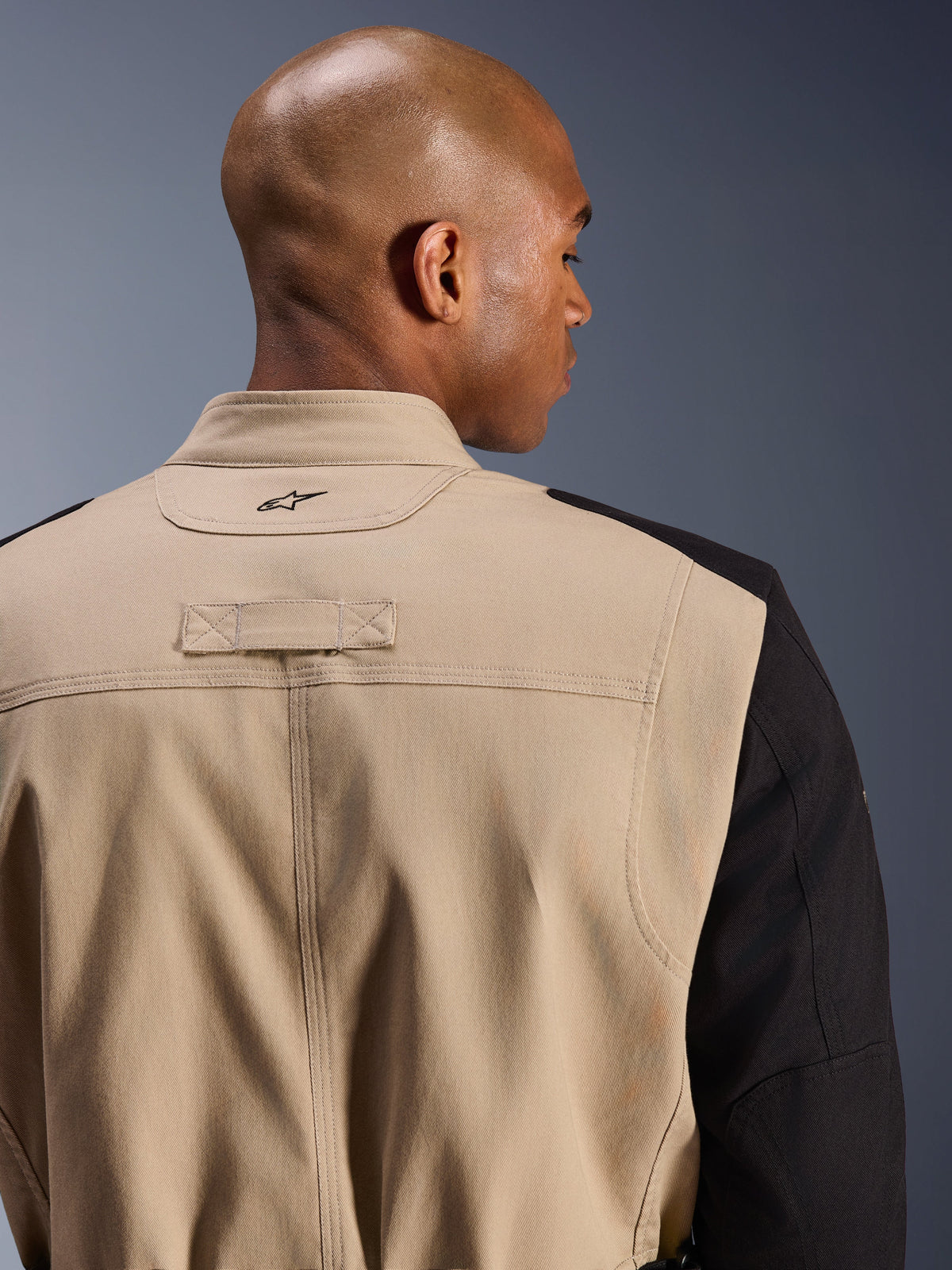 Alpinestars Dice Jacket, chaqueta urbana para motocicleta, canela y negro, detalle de primer plano del cuello posterior y el hombro, con logotipo bordado, construcción robusta de sarga de policotón, estilo workwear listo para la calle