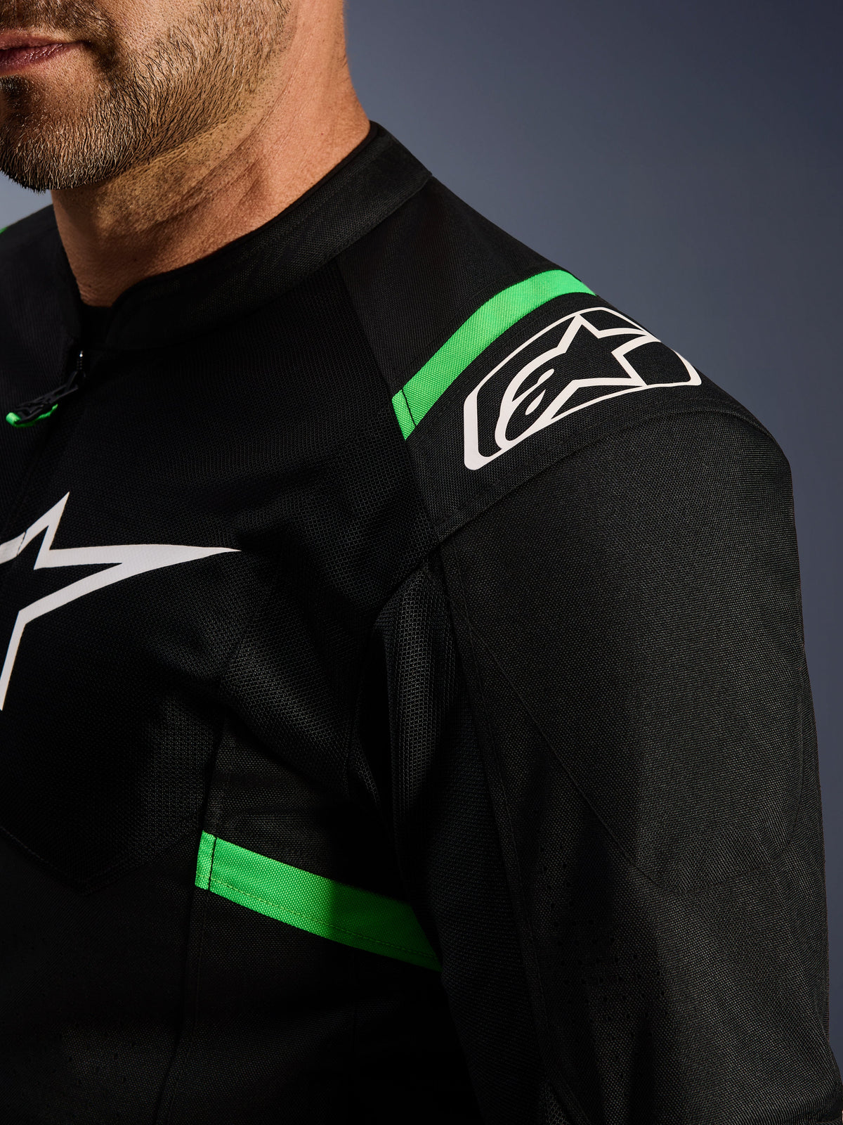 Chaqueta Alpinestars T-SPS Air V2, negra y verde flúor, primer plano del hombro y el pecho, logotipo de la estrella blanca de Alpinestars, tejido de malla técnica para el flujo de aire, chaqueta deportiva para motociclismo