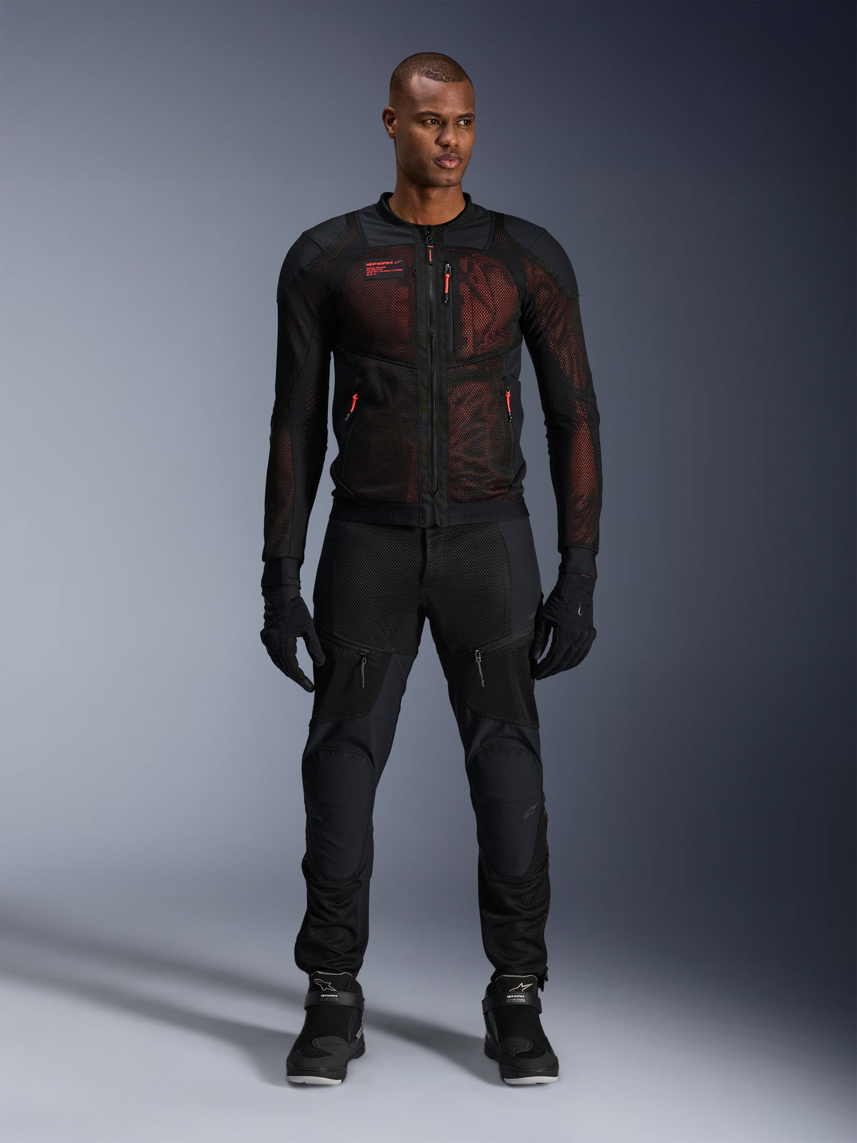 Alpinestars Troop-Air Pro Jacket, technical armored air jacket, Black and Red Fluo, worn by male model with matching riding pants and gloves, featuring high-flow mesh panels and red accents, urban motorcycle gear