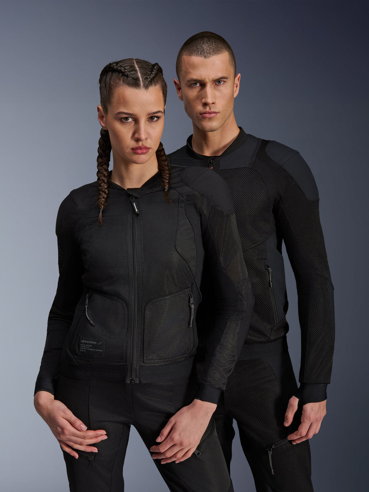 Chaqueta Alpinestars Troop-Air Pro, chaquetas de aire técnicas blindadas en color negro usadas por modelos masculino y femenino, con paneles de malla transpirable y protección integrada, equipamiento de moto urbano diseñado para climas cálidos.