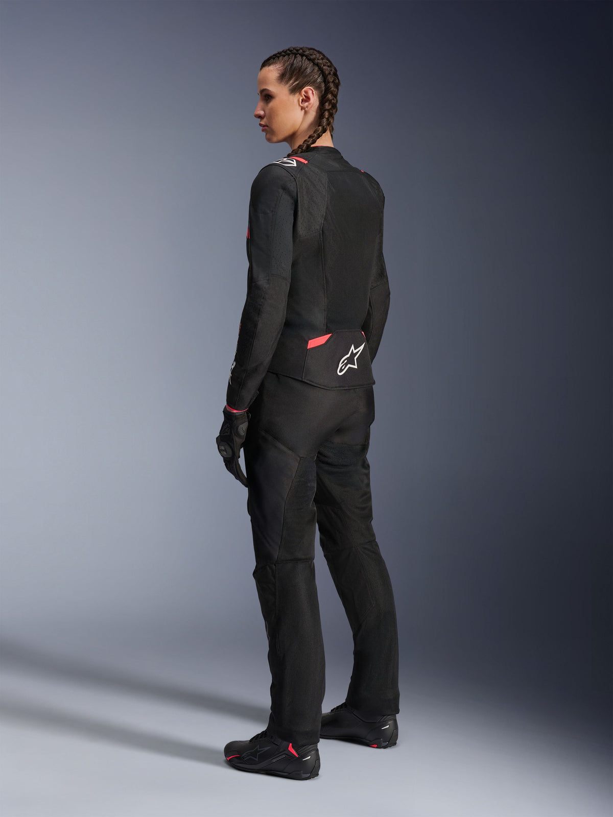 Alpinestars Woman Stella T-Sps Air v2 Jacket, Black and Diva Pink, textile motorcycle jacket shown from a rear-side view, featuring large mesh panels for airflow and white star logo on the back, worn with matching black riding pants, gloves, and boots.