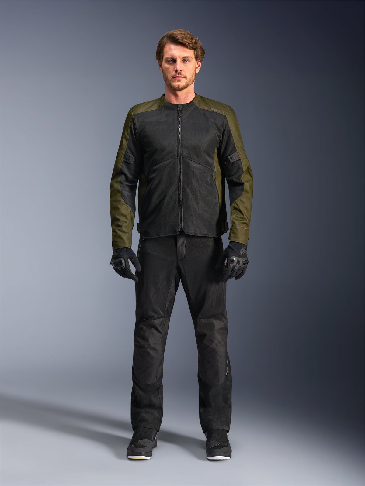 Chaqueta Alpinestars C-1 Air, caqui y negro, modelo masculino con pantalones de moto y guantes negros, diseño textil ligero con paneles de malla técnica, equipamiento de conducción urbano contemporáneo