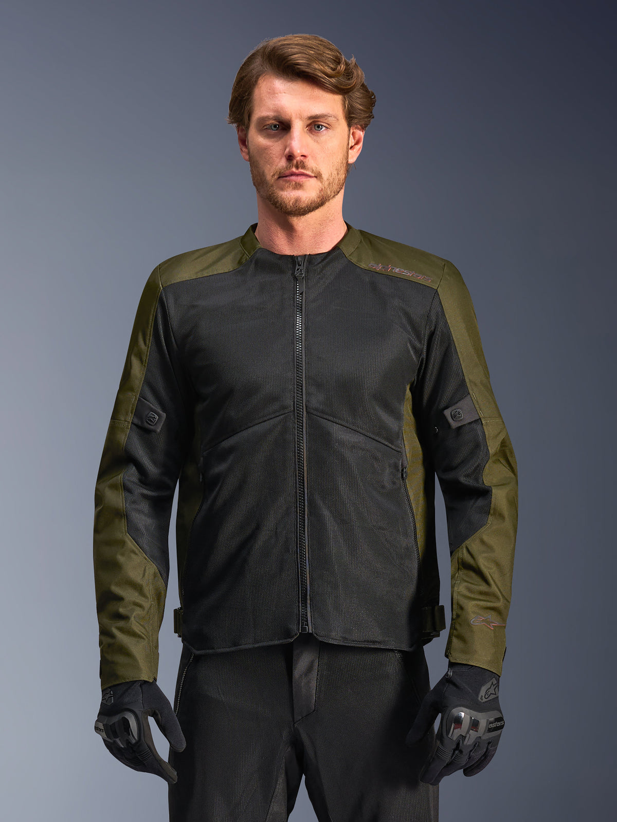 Chaqueta Alpinestars C-1 Air, caqui y negro, chaqueta de moto para hombre con grandes paneles de malla técnica para un flujo de aire máximo, usada por un modelo con pantalones y guantes de conducción negros, diseño urbano contemporáneo para desplazamientos.