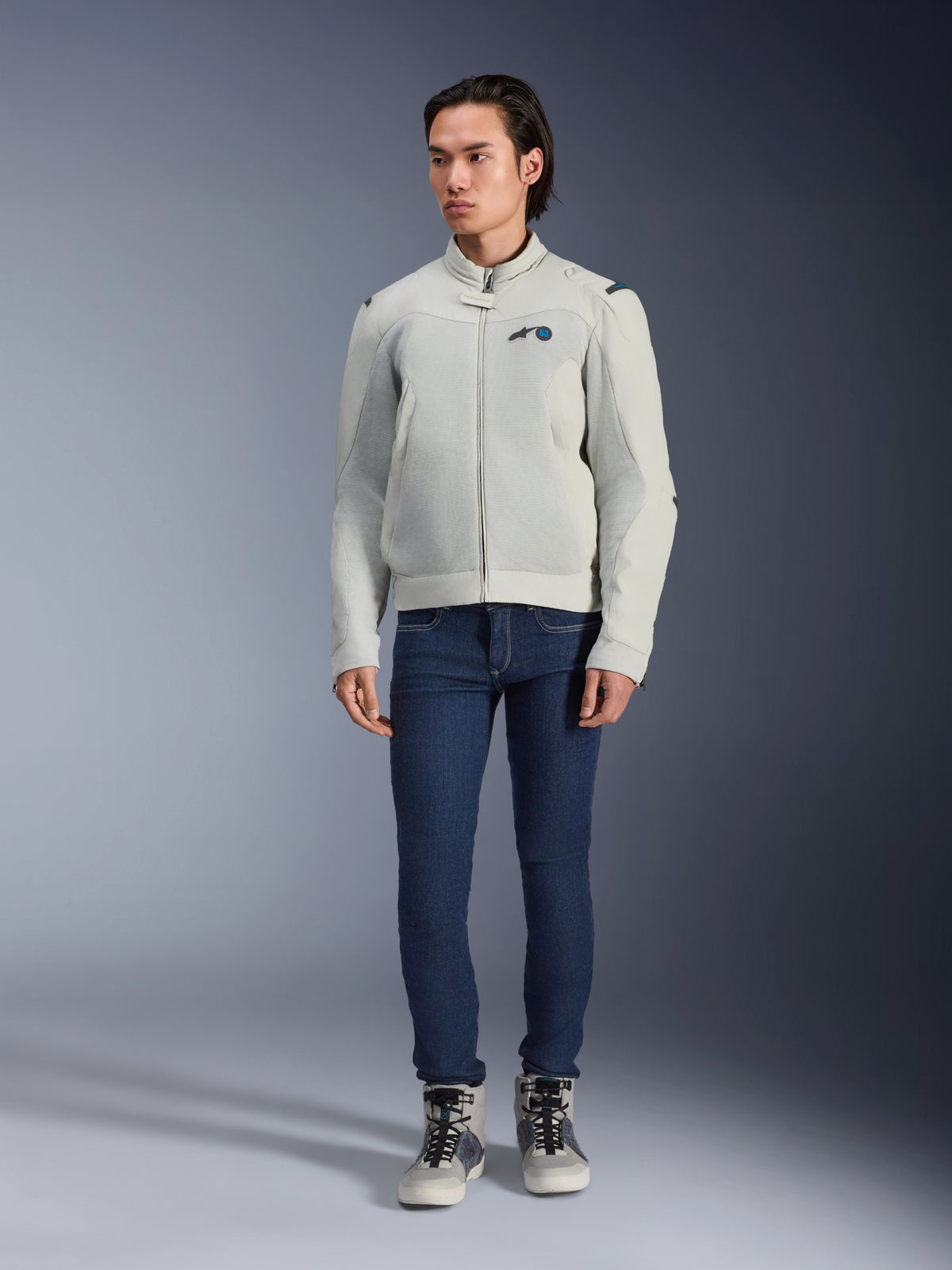Chaqueta Alpinestars Circal-1 Air, Metal Gray, chaqueta de moto urbana con paneles de malla para el flujo de aire, usada por un modelo con vaqueros azules y zapatillas de moto grises, diseño minimalista para una conducción urbana sostenible.
