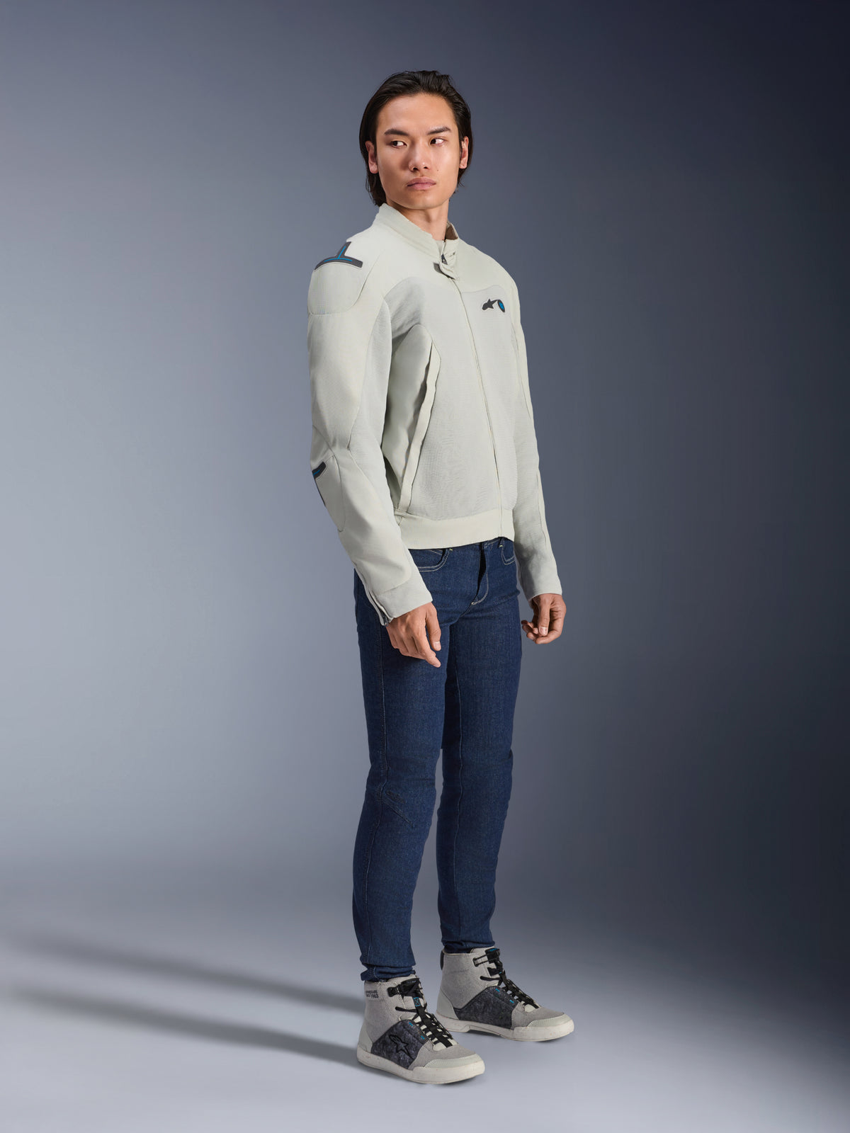 Chaqueta Alpinestars Circal-1 Air en gris metalizado y azul metilo, lucida por un modelo con vaqueros azul oscuro y zapatillas grises, chaqueta de moto urbana para verano con grandes paneles de malla para flujo de aire y un diseño minimalista.