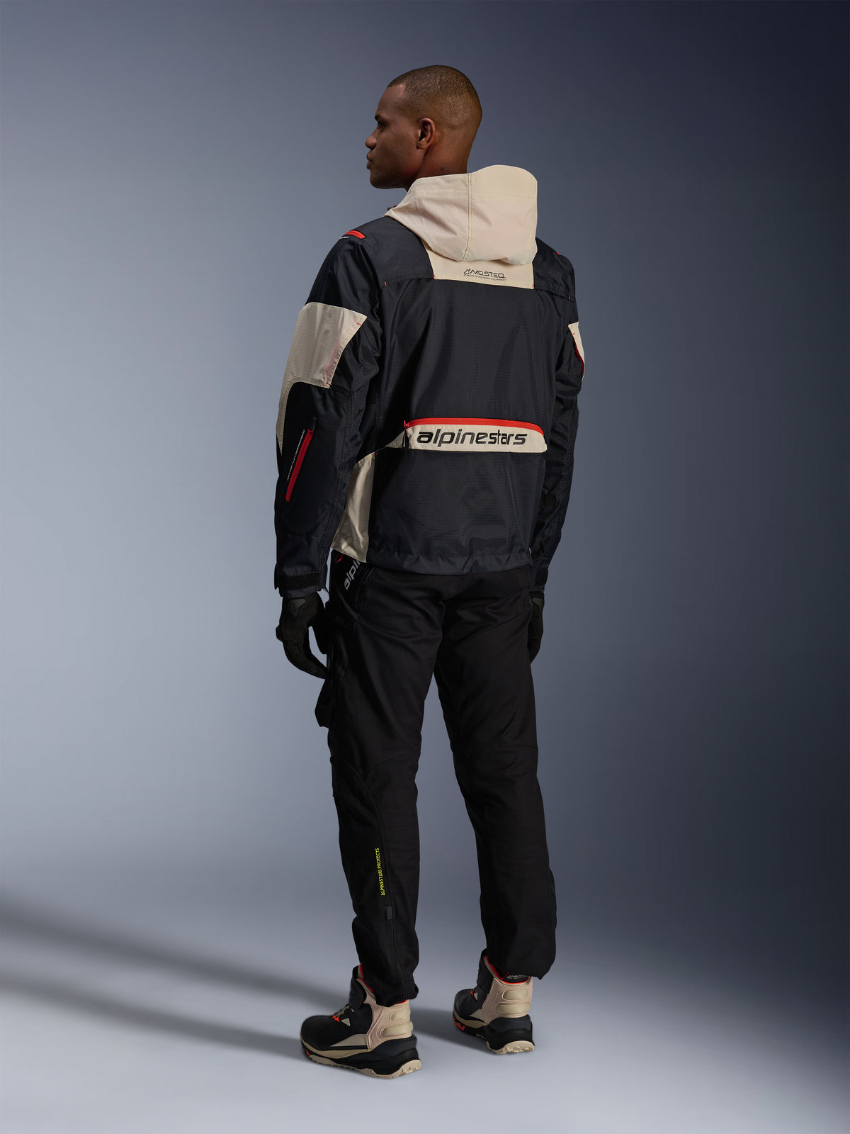 Alpinestars Mogress Air, chaqueta de moto urbana para hombre, negra y almendra con detalles naranja intenso, vista trasera.