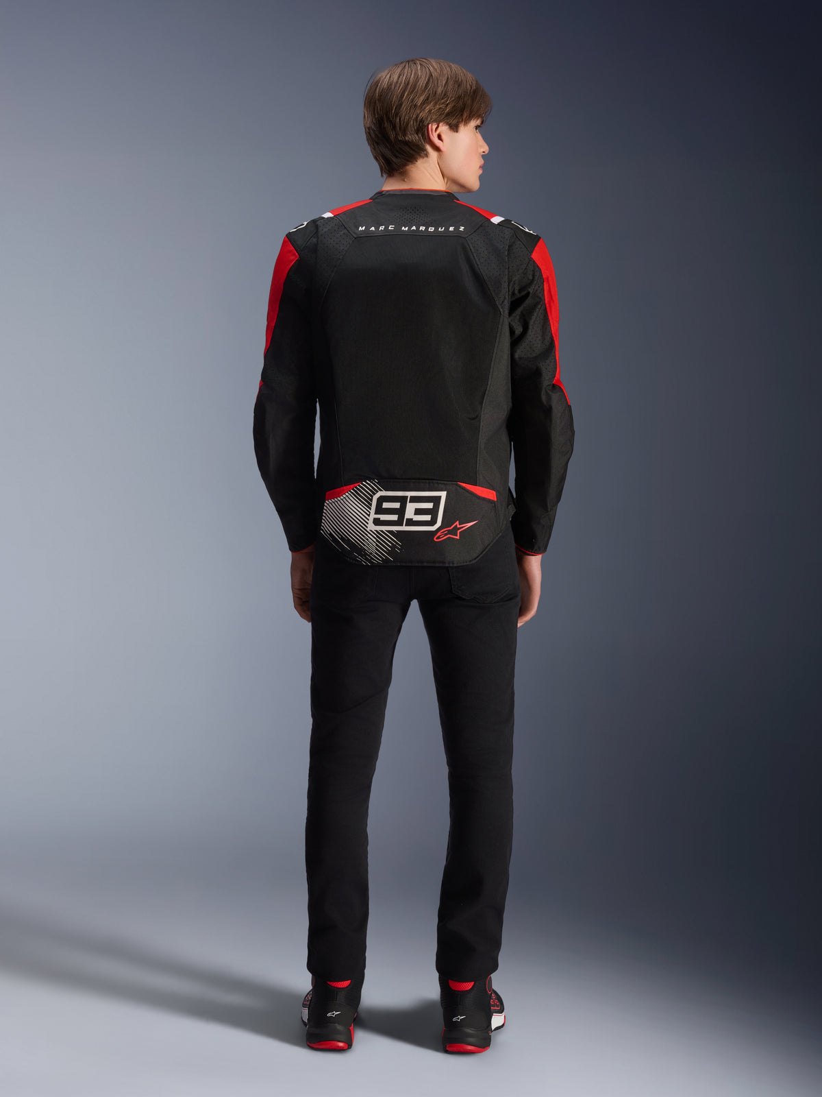 Alpinestars MM93 T-SPS Air V2 Jacket, Rear view on model, Black with Bright Red and White accents, featuring Marc Marquez signature branding and 93 logo on the back, performance textile motorcycle jacket for urban riding.