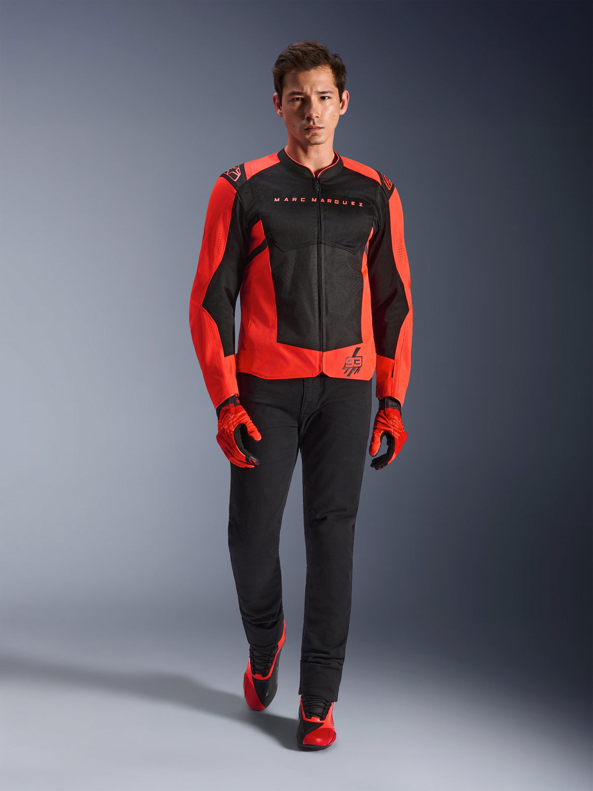Alpinestars MM93 T-SPS Air V2 Jacket, Red Fluo and Black, worn by a model with matching red gloves and black pants, featuring Marc Marquez branding and the 93 logo, ventilated sport motorcycle jacket for urban riding