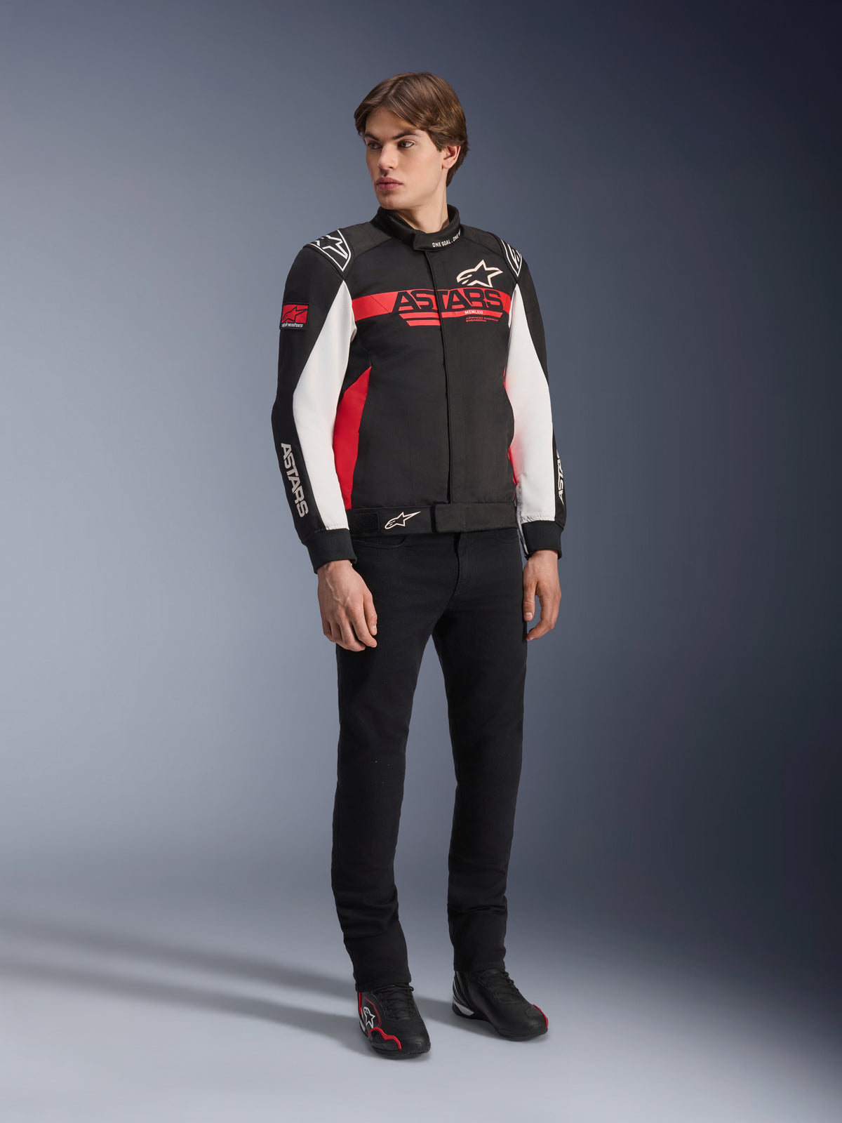 Alpinestars Monza Sport Jacket, Black Bright Red and White, textile motorcycle jacket, racing-inspired design with ASTARS branding across the chest and sleeves, worn by a model with black pants and riding shoes, casual sport riding gear