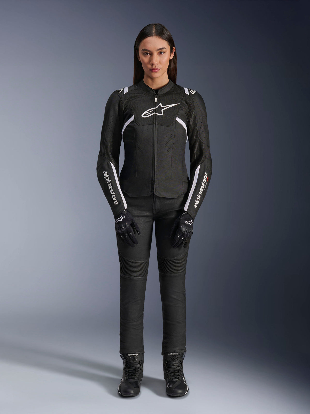 Chaqueta Alpinestars Stella T-Sps Air V2, chaqueta de moto para mujer, negra y blanca, con paneles de malla y detalles blancos, usada con pantalones, guantes y botas negros, ajuste deportivo para conducción urbana