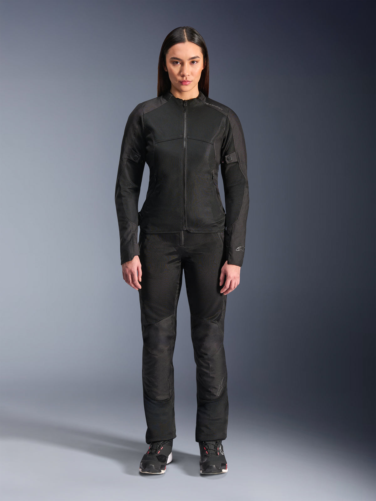 Mujer vistiendo la chaqueta Alpinestars Stella C-1 Air en negro, combinada con pantalones textiles de moto y calzado de conducción a juego, con un diseño urbano elegante y amplios paneles de malla para el flujo de aire.