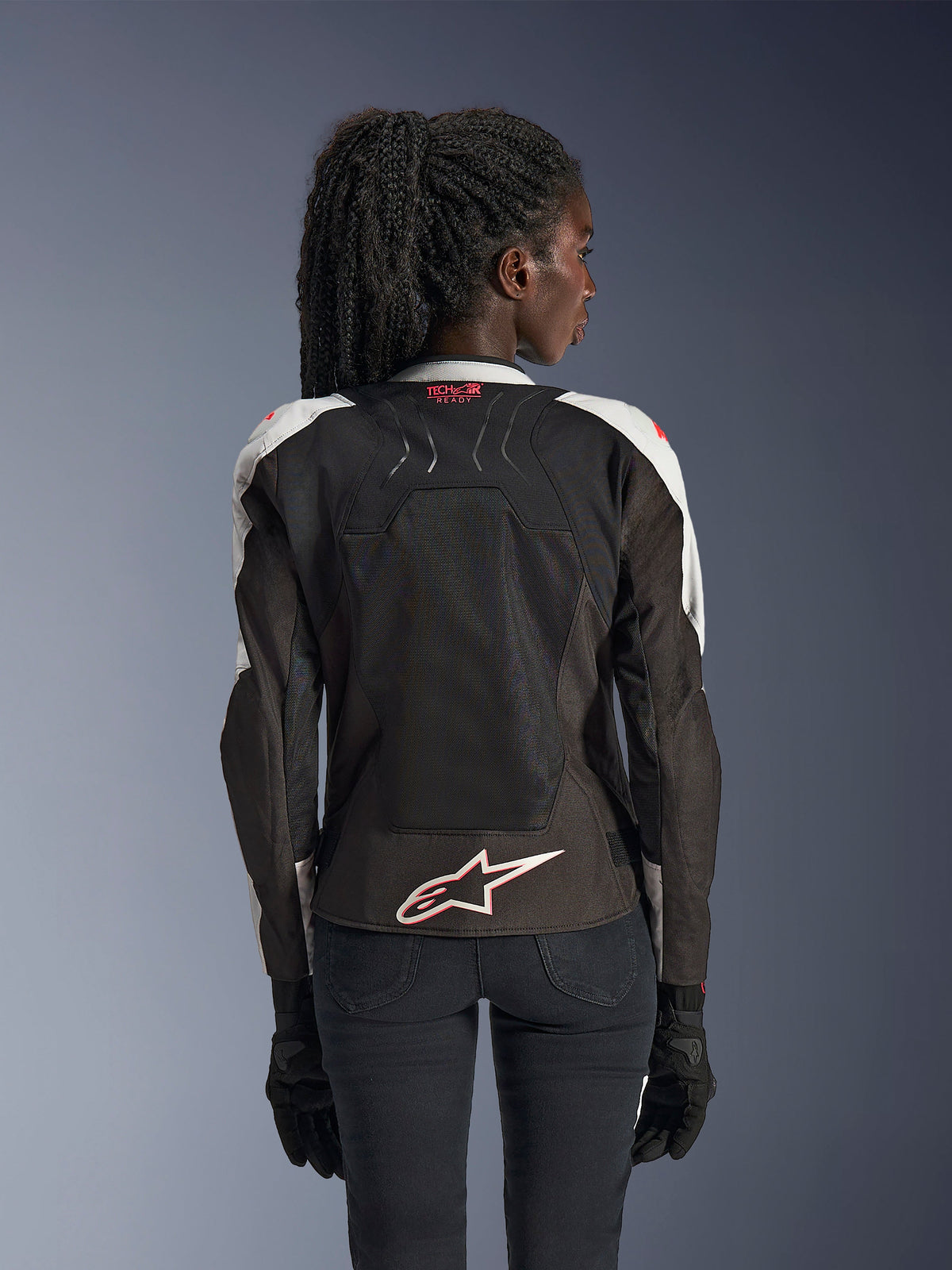 Chaqueta Alpinestars Stella SMX Air, chaqueta de motociclismo para mujer, gris hielo y negro con acentos en Coral Fluo, vista trasera que muestra la marca Tech-Air Ready y el logotipo Astar blanco, chasis de malla para una alta ventilación y ajuste de estilo deportivo