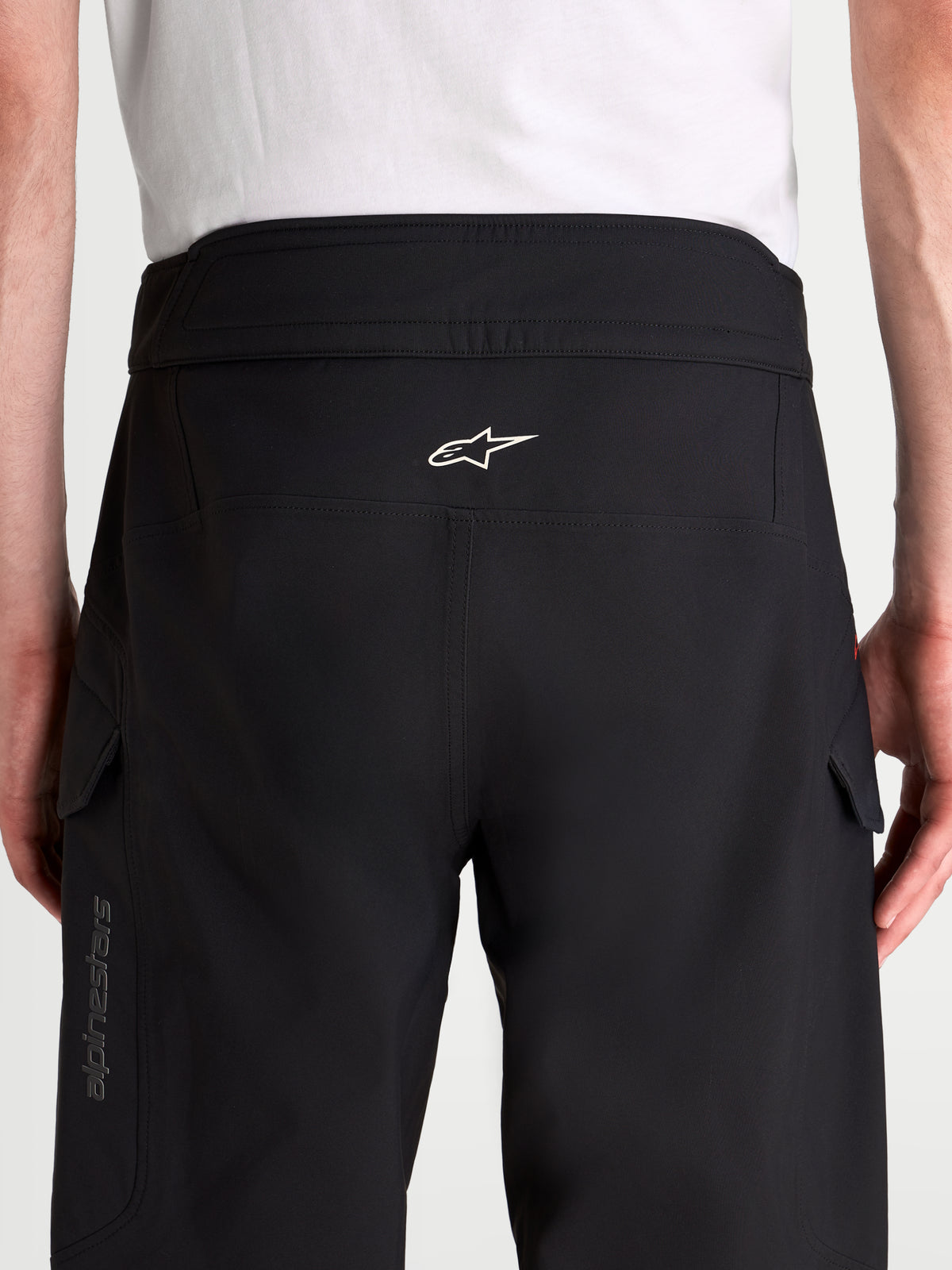 Alpinestars Juggernaut V2 Drystar Pantalones, pantalones de moto urbanos impermeables para hombre, negros, vista trasera con cintura alta, estructura ergonómica, logotipo blanco de Alpinestars y bolsillos cargo en modelo