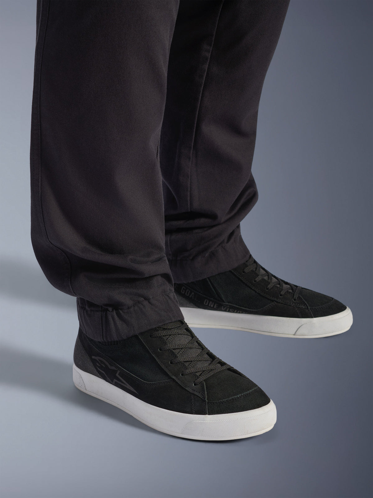 Alpinestars Flex-AST Cargo Pants - Short, pantalones urbanos para moto, negros, con piernas cónicas y dobladillos elásticos, combinados con zapatillas Alpinestars negras, estilo de conducción urbano contemporáneo