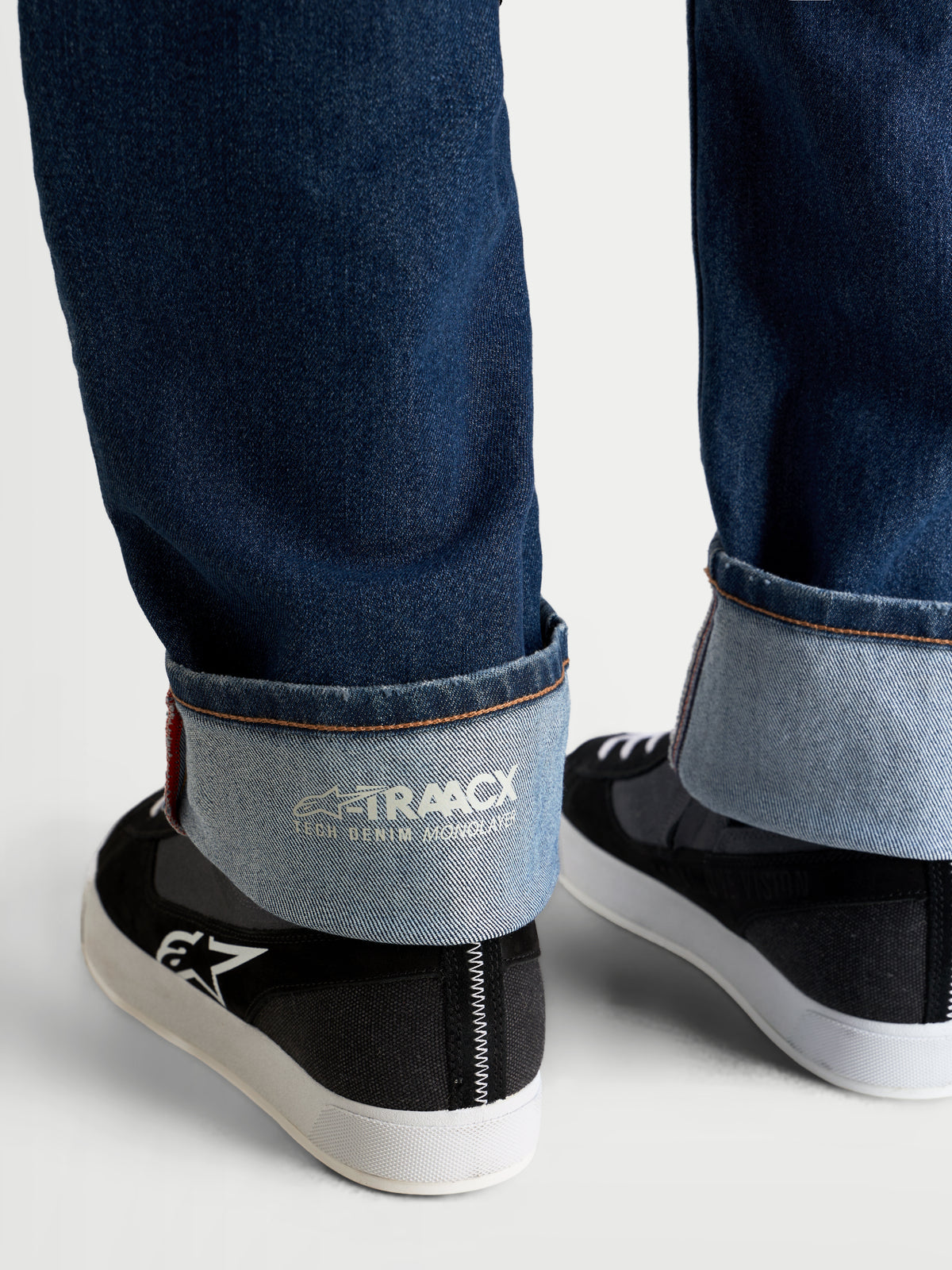 Alpinestars Flex-AST 8 Denim Pantalones, pantalones de moto vaqueros en azul medio, vista de cerca del dobladillo con vuelta que muestra la marca interna A-TRAACX de denim técnico monocapa