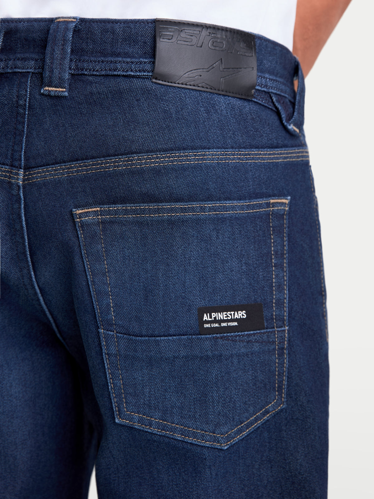 Alpinestars Flex-AST 7 Denim Pants, men's urban motorcycle jeans in dark blue, close-up back view showing leather waistband patch, rear pockets with Alpinestars branding, and single-layer technical construction, AA certified road riding apparel