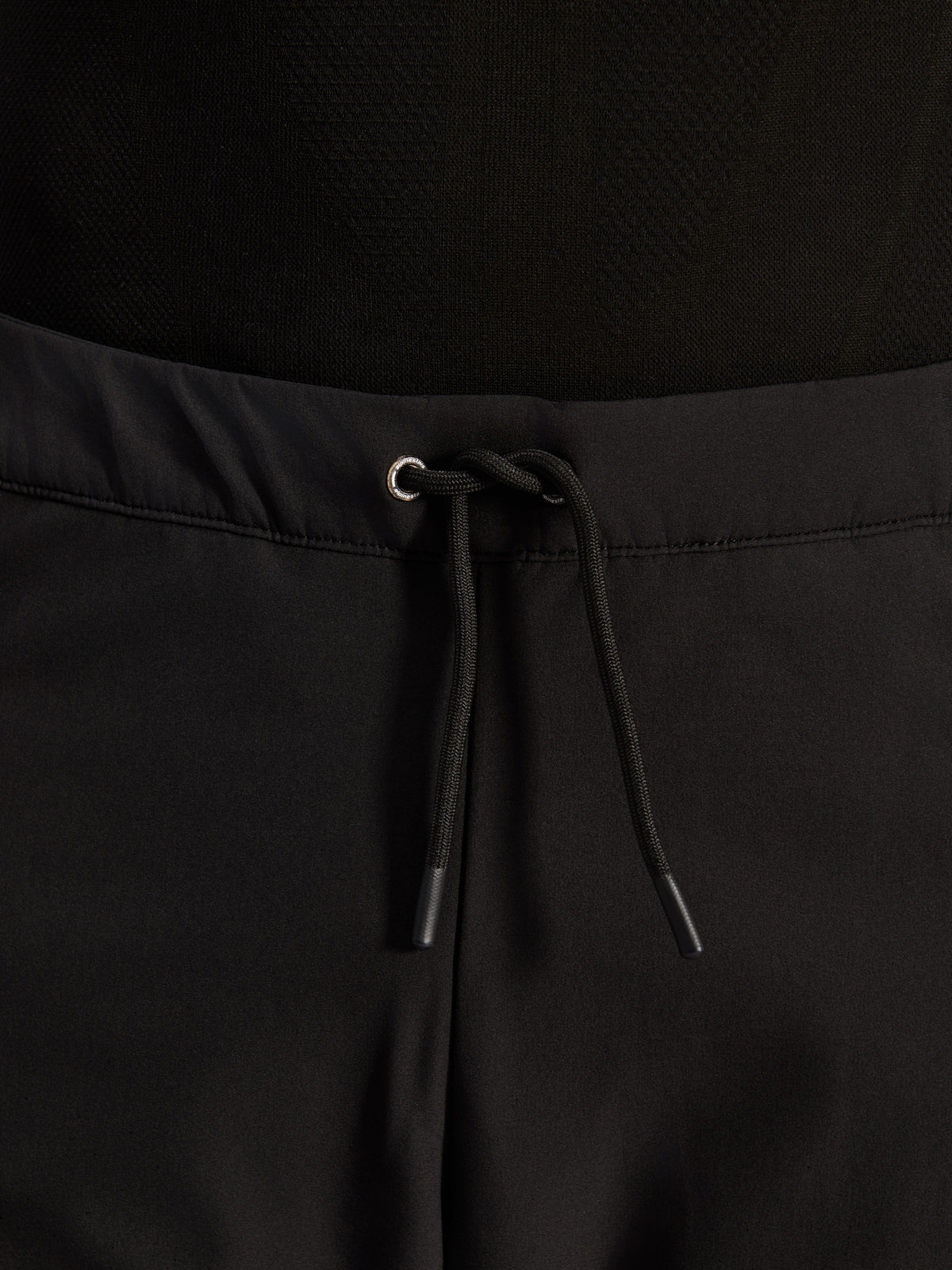 Alpinestars Aeroshell Airflow Pants, negros, primer plano de la cintura con cordón elástico interno ajustable y detalle de ojal plateado, equipamiento de motociclismo sport-touring