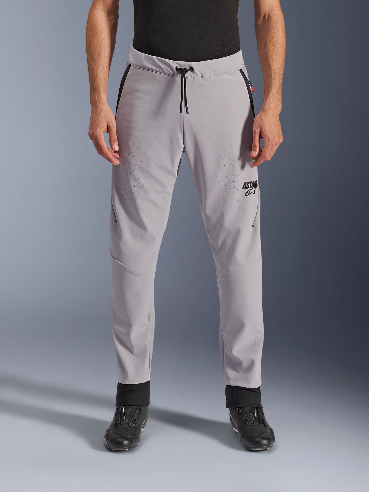 Pantalones Alpinestars Aeroshell Airflow, Gris Medio, vista frontal con zonas perforadas con láser en los muslos y las espinillas, cintura con cordón negro y logotipo ASTARS negro, chasis de softshell ligero para conducir en climas cálidos
