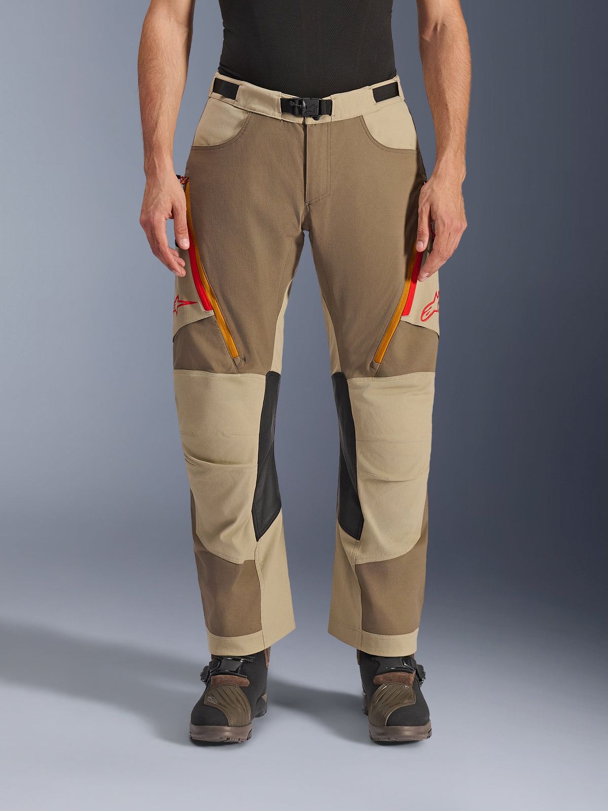 Pantalones Alpinestars Maxdura Dual, Walnut Aluminum, pantalones de moto de aventura con ventilaciones en los muslos con cremalleras rojas y naranjas, paneles interiores de cuero negro en las rodillas, usados con una capa base negra y botas robustas, diseño multitonal duradero para conducción dual-sport