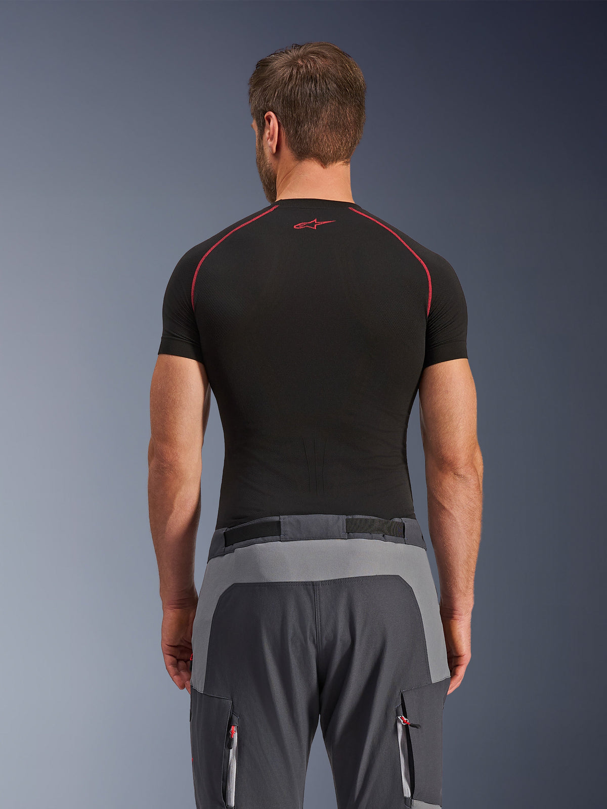 Alpinestars Maxdura Dual Pants, Adventure Motorcycle Pants, Dark Gray and Deep Gray, rear view showing reinforced panels on the seat and waist, worn with a black short-sleeve base layer, featuring zippered pockets with red details