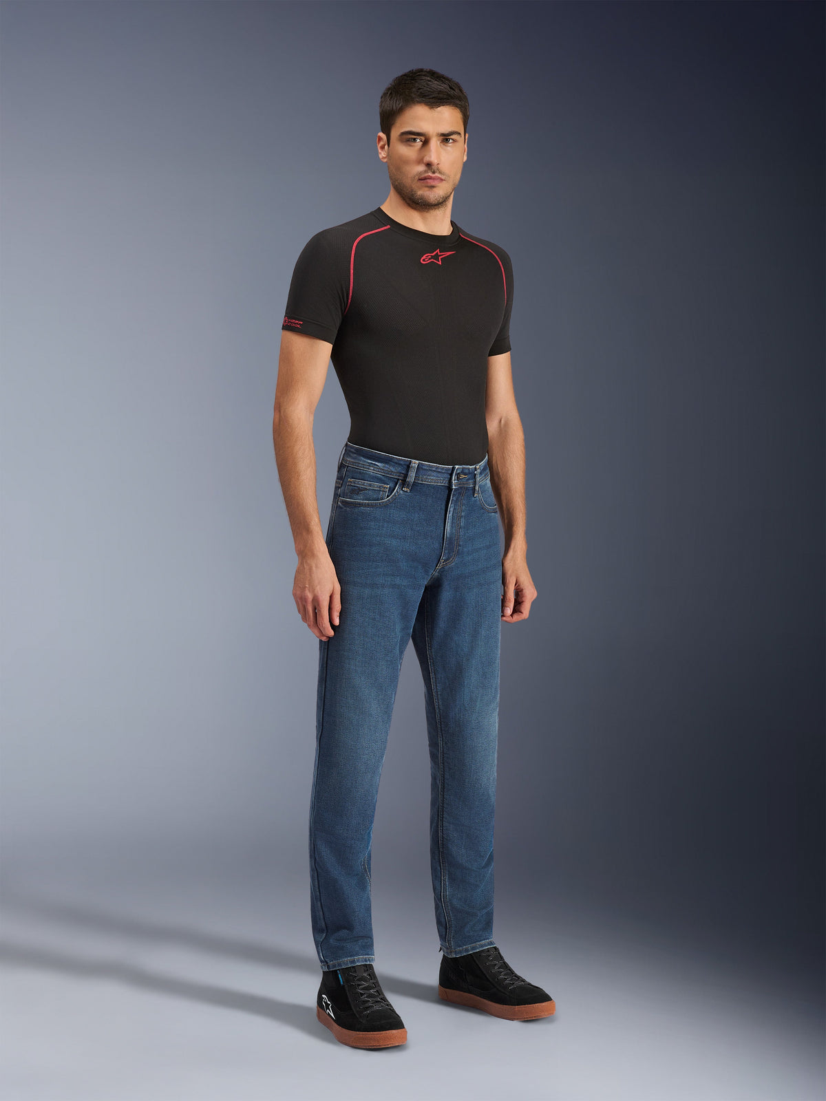 Alpinestars Flex-AST 5 Denim Pants - Short, Indigo Washed, vaqueros urbanos para motocicleta con ajuste cónico, usados por un modelo masculino con camiseta negra ajustada y zapatillas negras, estilo denim clásico para transiciones de la carretera a la calle