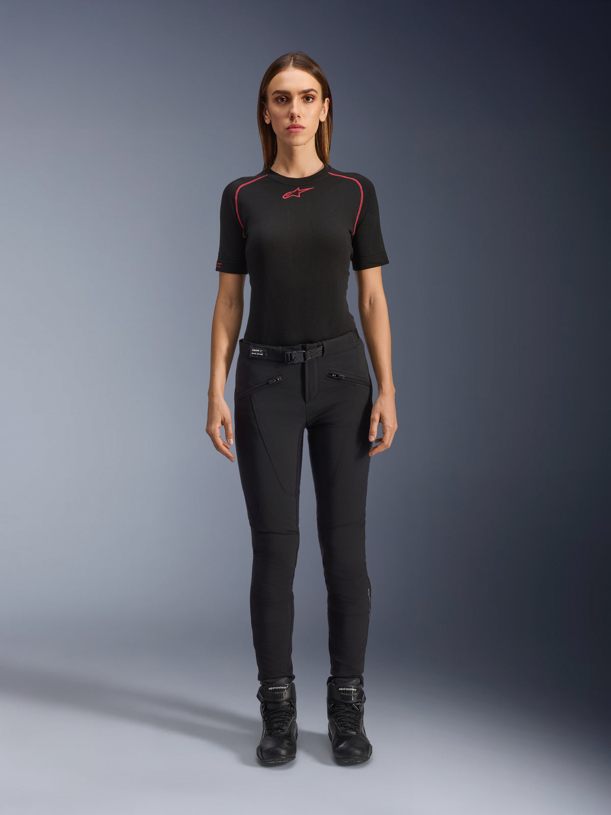 Alpinestars Alamosa Women Pants, slim-fit black motorcycle riding pants, shown on a model facing forward, featuring zippered front pockets and an integrated waist belt, minimalistic streetwear-inspired style for urban riding