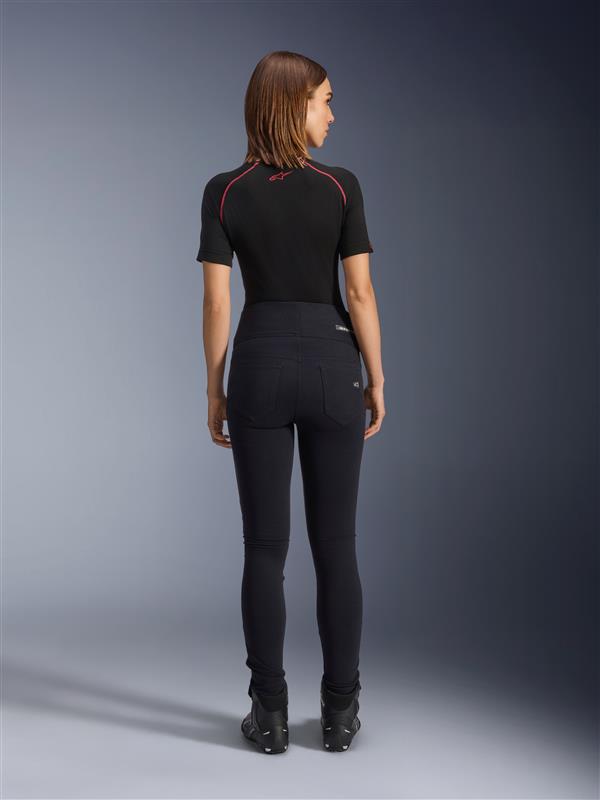 Leggings Alpinestars Stella Flex-Ast, leggings de moto para mujer, negros, vista trasera que muestra el ajuste entallado de cintura alta, combinados con una camiseta negra de manga corta y botas de motorista negras, equipamiento para conducción urbana