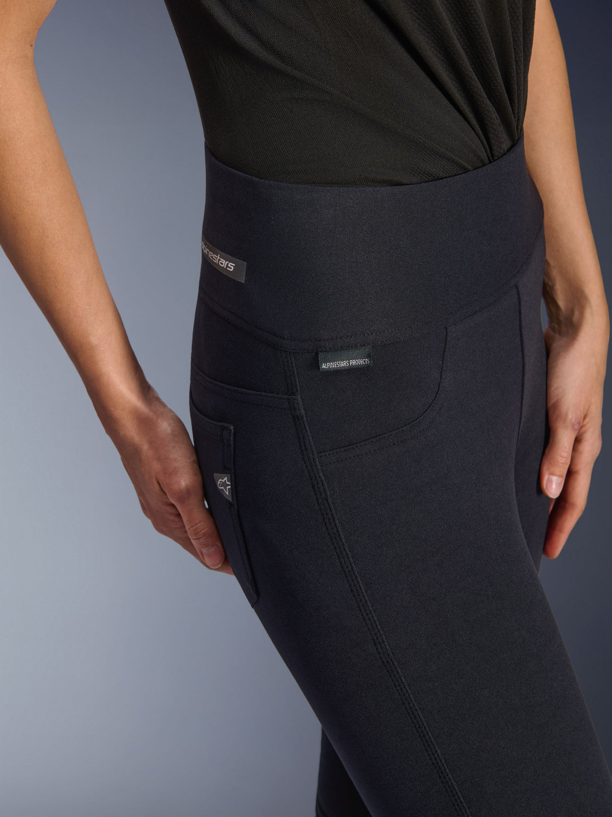 Leggings Stella Flex-AST para mujer de Alpinestars, pantalones de moto de talle alto en color negro, primer plano de la zona de la cadera con la etiqueta jacquard, costuras laterales con triple pespunte y detalle de bolsillo inspirado en el estilo denim, ropa de conducción urbana para mujer