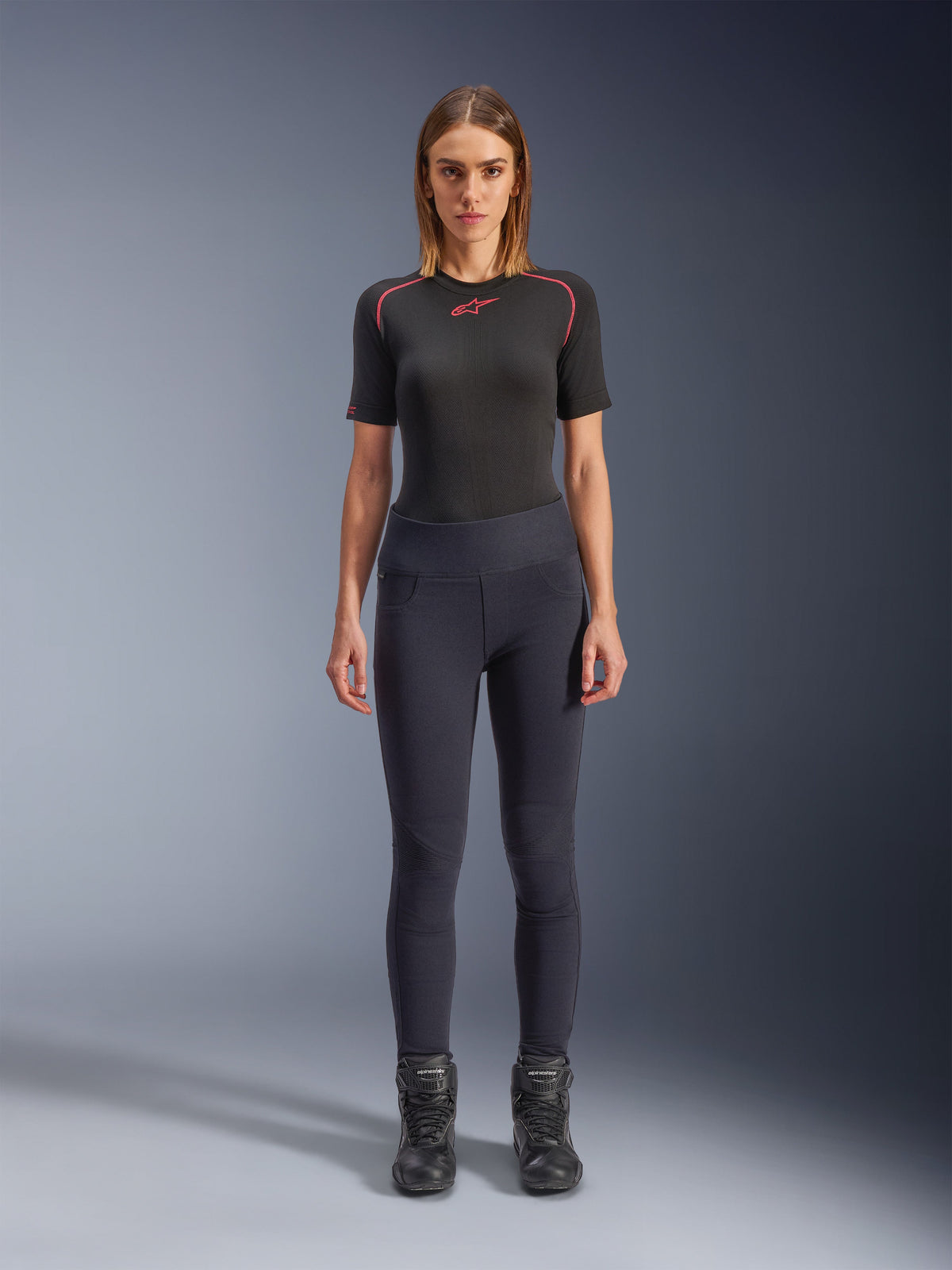 Alpinestars Stella Flex-Ast Leggings, leggings de moto para mujer, negros, combinados con una camiseta de manga corta negra con detalles rojos y botas de moto negras, equipamiento urbano contemporáneo de corte entallado, vista frontal