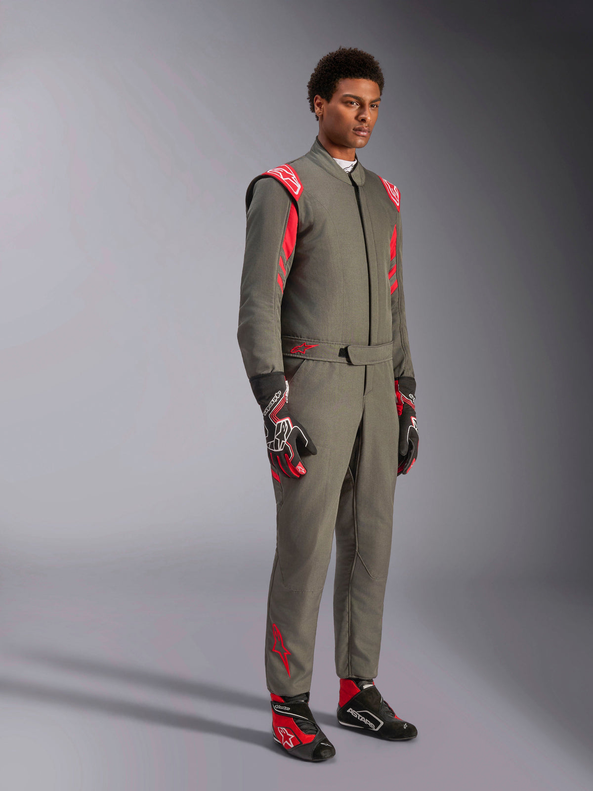 Mono Alpinestars GP Race V3 FIA, traje de automovilismo en color Anthracite Red, combinado con guantes y calzado de carreras a juego, con charreteras rojas en los hombros y logotipos de la marca, diseño técnico de dos capas para automovilismo