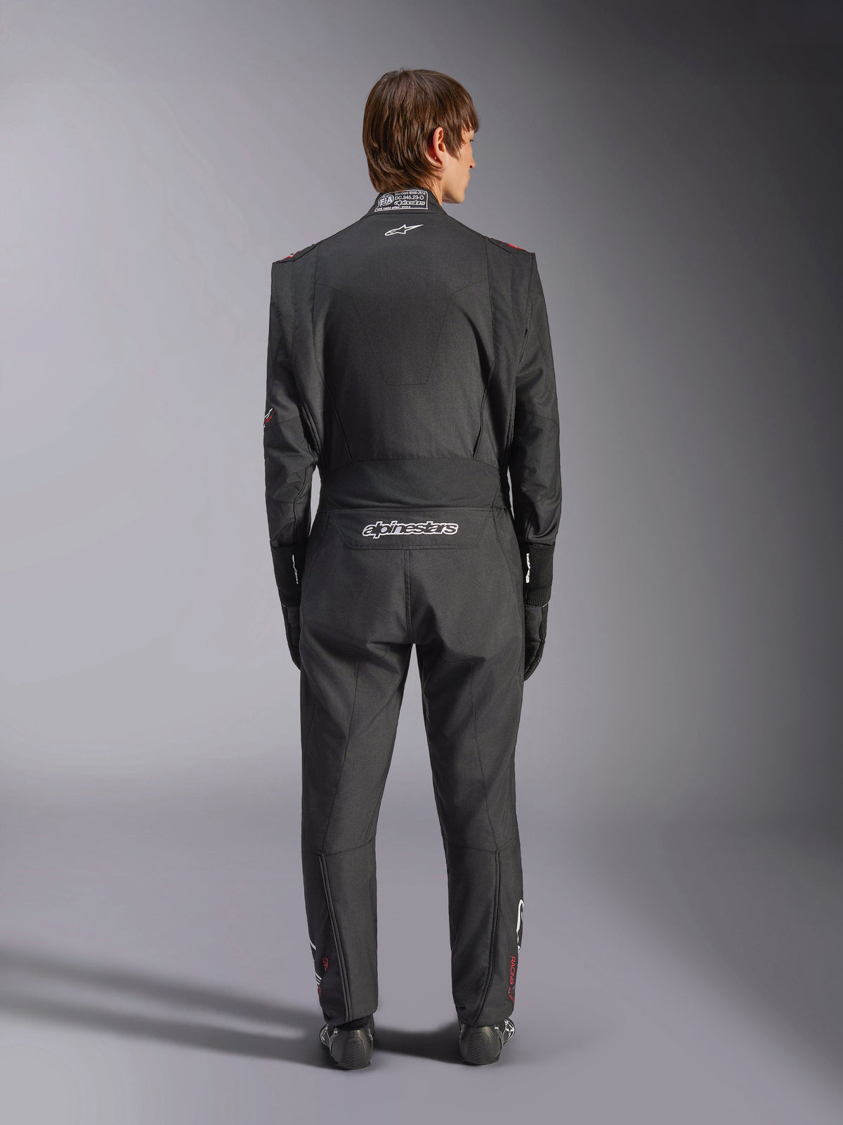 Mono Alpinestars GP Tech V4, traje de carreras de automovilismo, negro y blanco, vista trasera con marca Alpinestars en blanco y certificación FIA en el cuello, ajuste ergonómico para la protección de pilotos profesionales