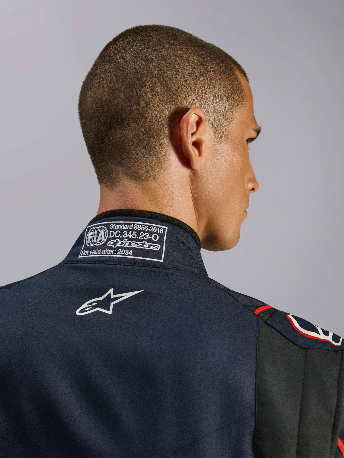 Alpinestars GP Tech V4 Suit in Blue Navy Black Red, close-up of the back collar featuring the FIA 8856-2018 certification label and white embroidered Alpinestars logo, high-performance auto racing suit detail