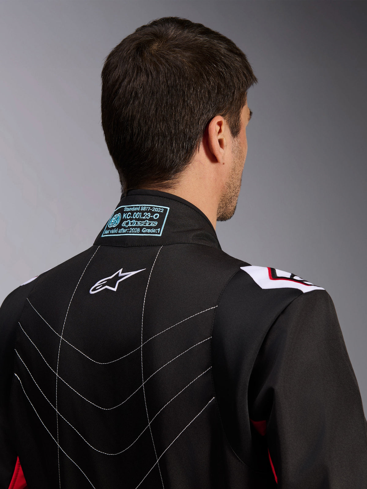 Mono Alpinestars KMX-9 V3, mono de karting, negro, rojo y blanco, vista trasera del cuello que muestra la etiqueta de homologación FIA 8877-2022, logotipo blanco de Astars y detalles de costuras decorativas