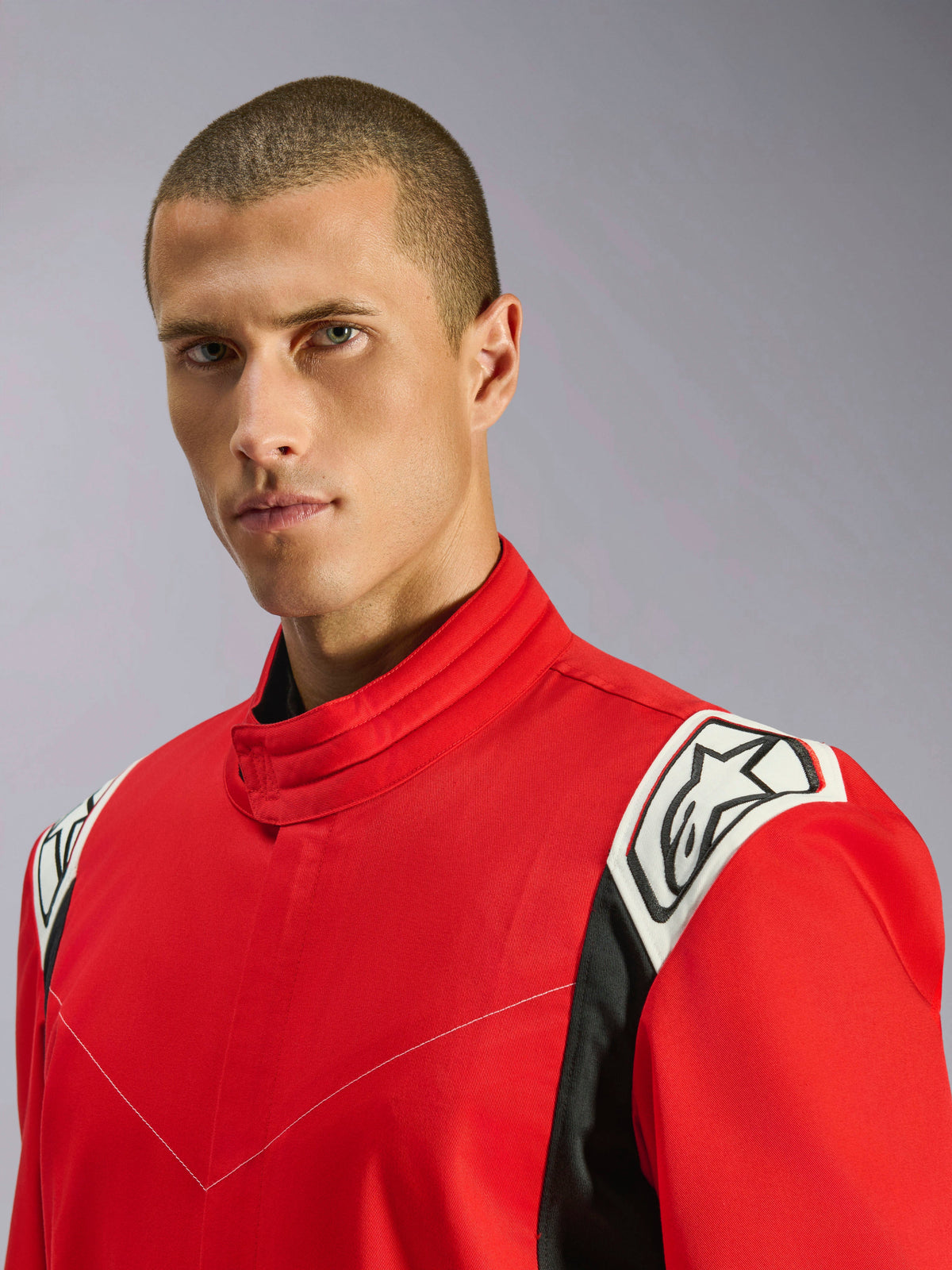 Alpinestars Kart Indoor V2 Suit in Red, close-up portrait of a male model wearing the suit, highlighting the ergonomic collar and white and black shoulder accents with the Alpinestars logo.